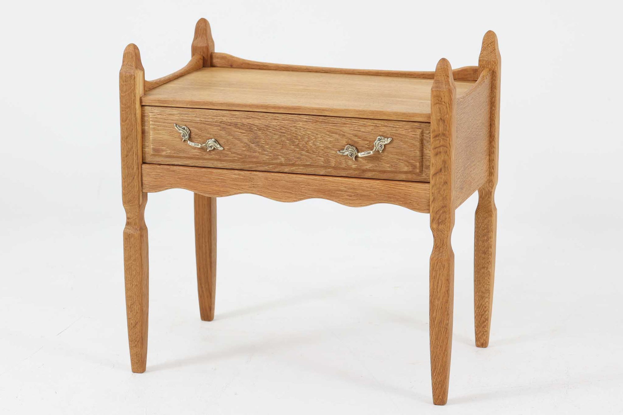 デンマークのデザイナー、Henning Kjaernulfによってデザインされたヴィンテージのサイドチェスト。素材には、木目の美しいオーク材が用いられており、しっかりとした存在感と温かみを感じさせます。脚部や幕板には柔らかな曲線が施され、ケアヌルフらしい彫刻的なフォルムが印象的。天板の縁や引き出しの装飾的なハンドルにもクラフトマンシップが光ります。引き出し1杯のシンプルな構造ながら、細部にこだわった造形が空間に個性を添える一台。ベッドサイドはもちろん、玄関先やリビングにもおすすめのアイテムです。