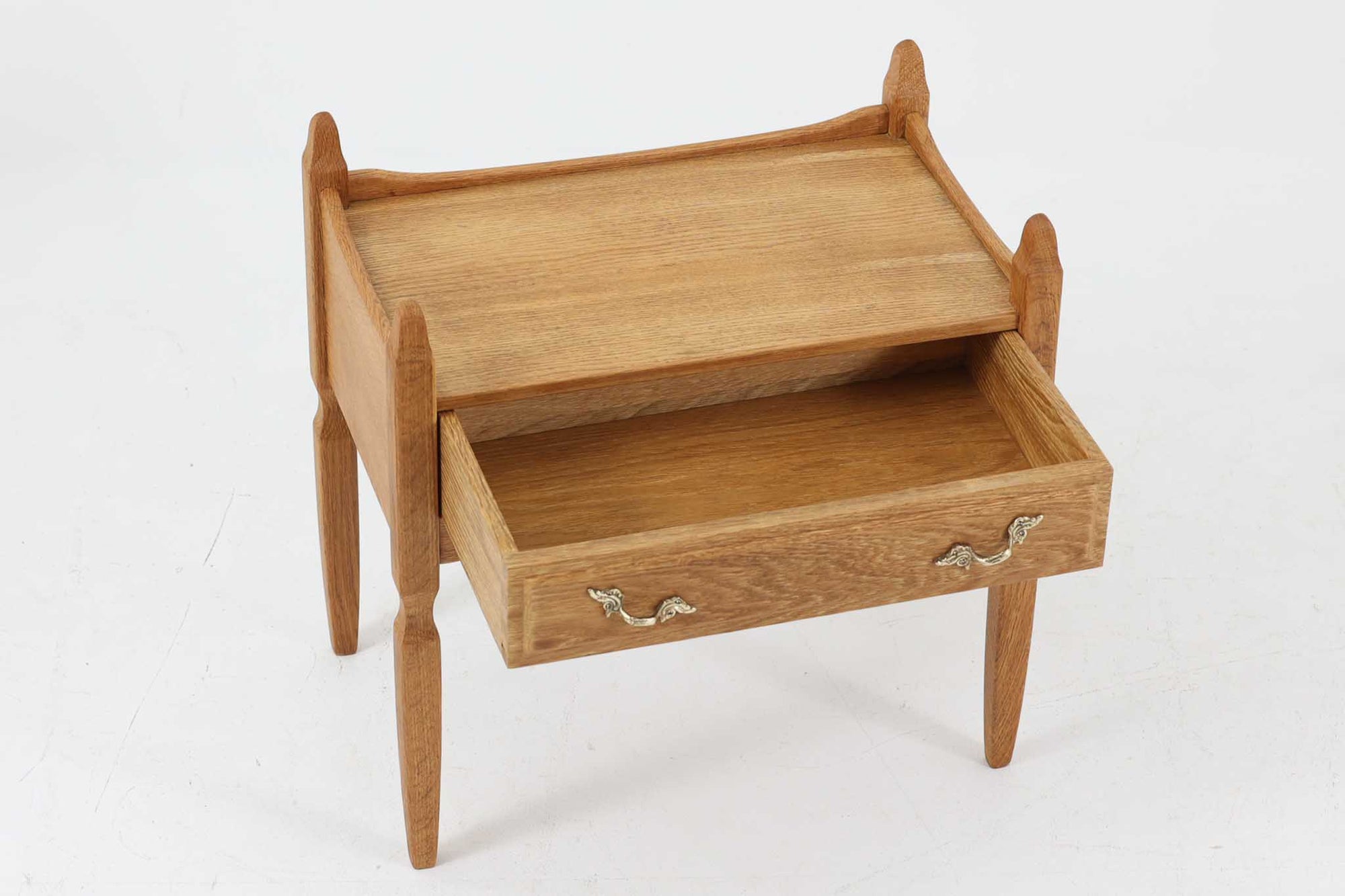 デンマークのデザイナー、Henning Kjaernulfによってデザインされたヴィンテージのサイドチェスト。素材には、木目の美しいオーク材が用いられており、しっかりとした存在感と温かみを感じさせます。脚部や幕板には柔らかな曲線が施され、ケアヌルフらしい彫刻的なフォルムが印象的。天板の縁や引き出しの装飾的なハンドルにもクラフトマンシップが光ります。引き出し1杯のシンプルな構造ながら、細部にこだわった造形が空間に個性を添える一台。ベッドサイドはもちろん、玄関先やリビングにもおすすめのアイテムです。