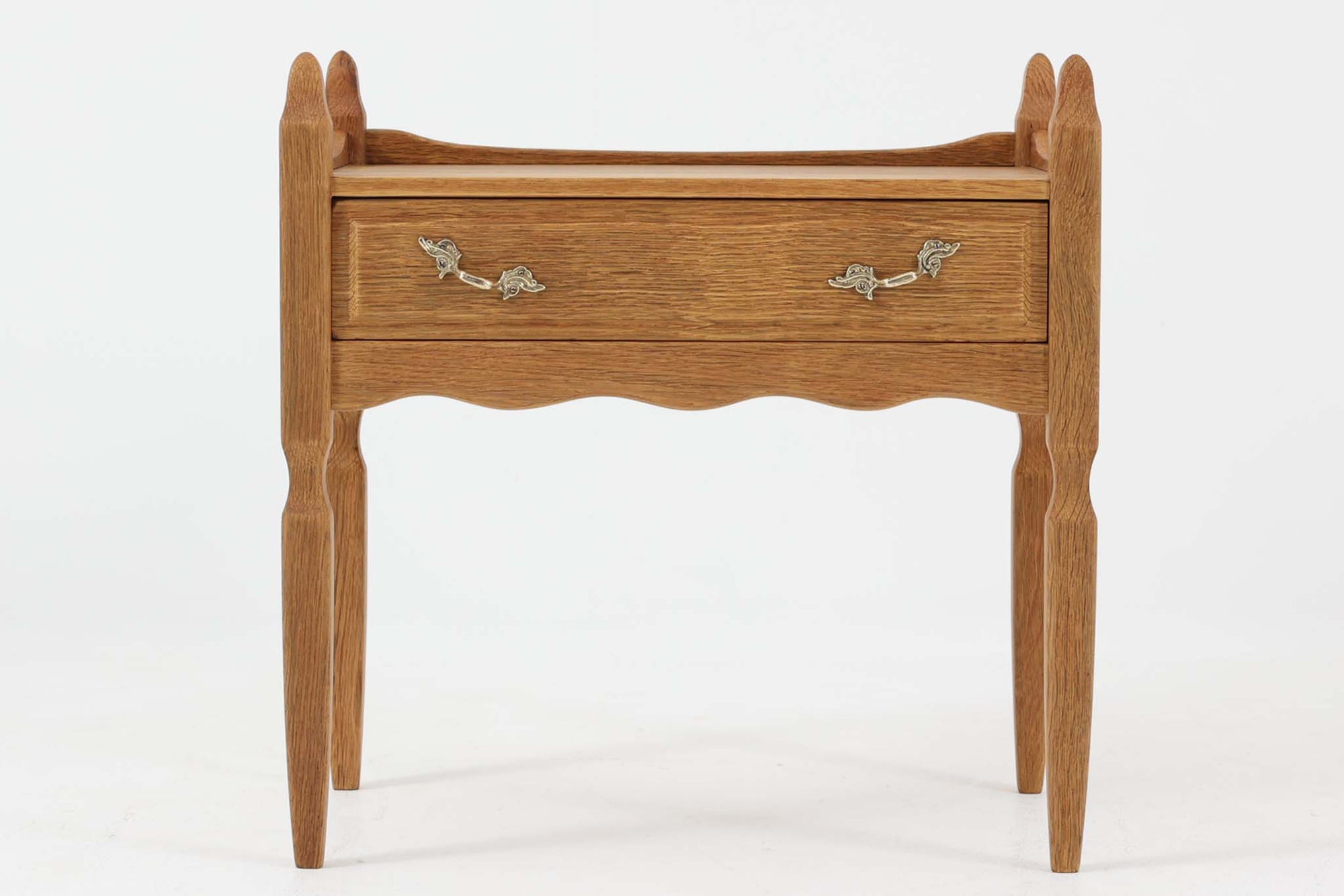 デンマークのデザイナー、Henning Kjaernulfによってデザインされたヴィンテージのサイドチェスト。素材には、木目の美しいオーク材が用いられており、しっかりとした存在感と温かみを感じさせます。脚部や幕板には柔らかな曲線が施され、ケアヌルフらしい彫刻的なフォルムが印象的。天板の縁や引き出しの装飾的なハンドルにもクラフトマンシップが光ります。引き出し1杯のシンプルな構造ながら、細部にこだわった造形が空間に個性を添える一台。ベッドサイドはもちろん、玄関先やリビングにもおすすめのアイテムです。※背面が前オーナーにより一部カットされているため、価格に反映しております。