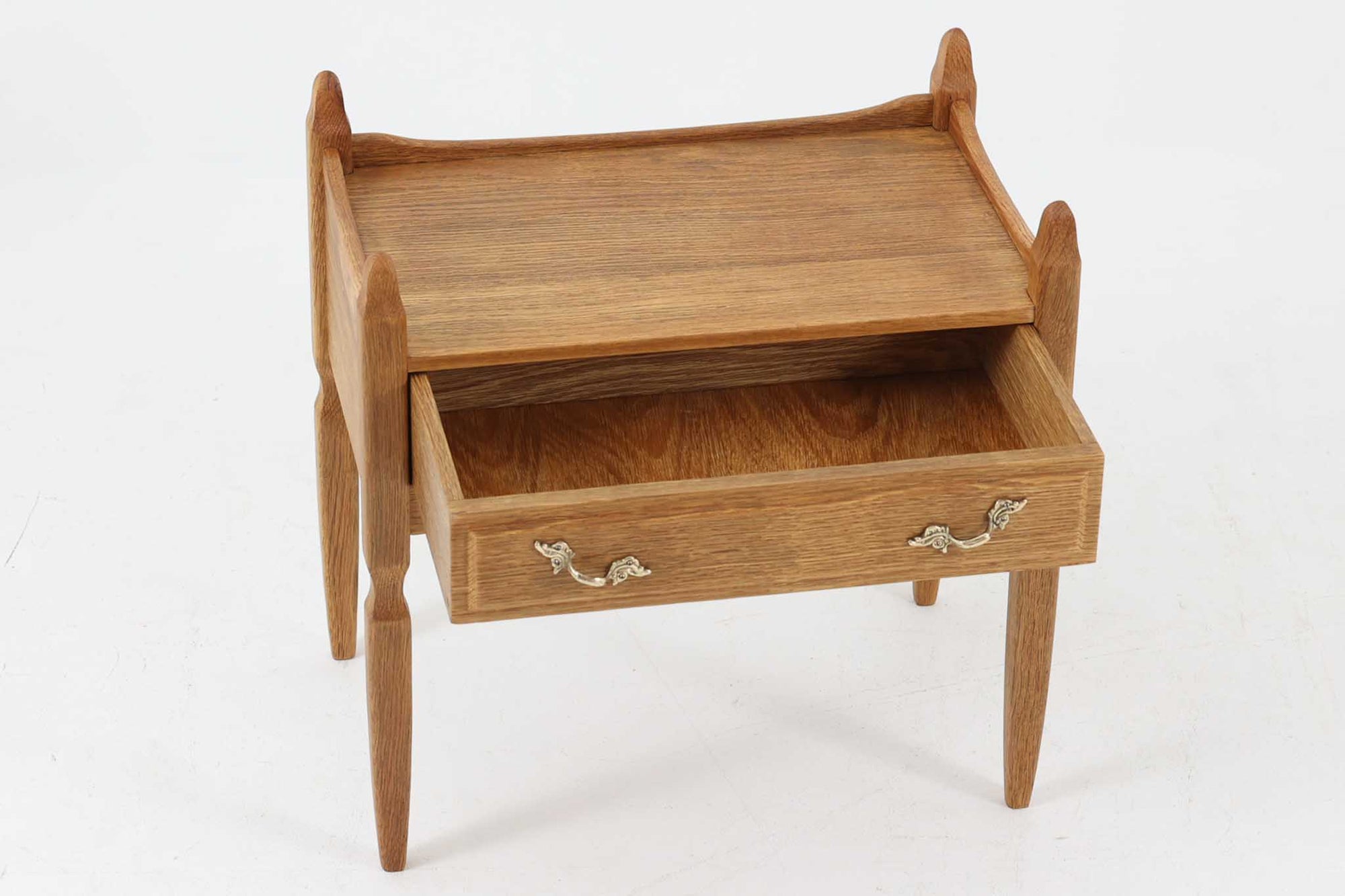 デンマークのデザイナー、Henning Kjaernulfによってデザインされたヴィンテージのサイドチェスト。素材には、木目の美しいオーク材が用いられており、しっかりとした存在感と温かみを感じさせます。脚部や幕板には柔らかな曲線が施され、ケアヌルフらしい彫刻的なフォルムが印象的。天板の縁や引き出しの装飾的なハンドルにもクラフトマンシップが光ります。引き出し1杯のシンプルな構造ながら、細部にこだわった造形が空間に個性を添える一台。ベッドサイドはもちろん、玄関先やリビングにもおすすめのアイテムです。※背面が前オーナーにより一部カットされているため、価格に反映しております。