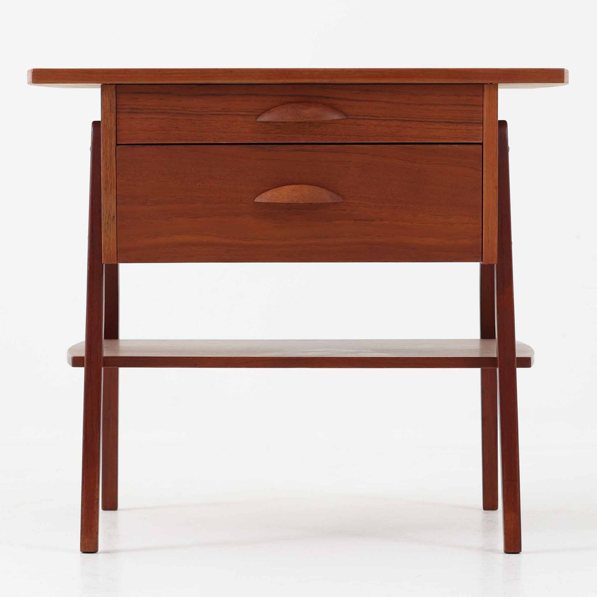 チーク材を用いたこちらの2段チェストは、緩やかにカーブした天板と舟形の引き手が特徴的な北欧ビンテージ家具です。幅64cmとコンパクトながらも引き出し2杯と下部の棚板を備え、収納力とディスプレイ性を兼ね備えています。テーパー脚が軽やかな印象を与え、ベッドサイドやリビングのサイドテーブルとしても活躍。年月を経た木肌の温かみが、空間に落ち着きと味わい深い存在感をもたらす一品です。