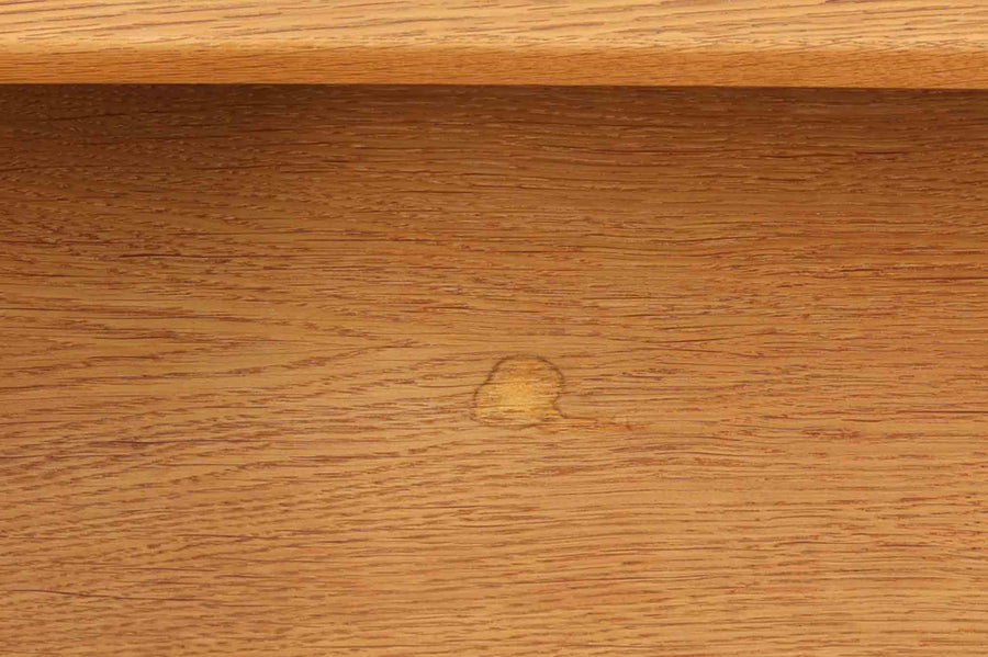 デンマークを代表する家具デザイナー、Hans J. Wegner（ハンス・J・ウェグナー）によってデザインされた、Ry mobler社製のビンテージサイドテーブルです。素材にはあたたかみのあるオーク材が用いられており、北欧らしいシンプルかつ機能的な美しさが感じられます。天板は縁に立ち上がりがあり、物が転がり落ちにくい仕様。引き出しとオープンスペースが組み合わされた実用的な構造で、ベッドサイドやソファ横、玄関周りなど様々なシーンで活躍します。無駄のないデザインと丸脚の柔らかな佇まいが魅力で、ウェグナーデザインならではのバランス感が光る一台です。