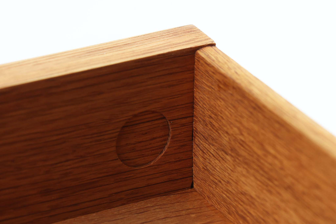 デンマークを代表する家具デザイナー、Hans J. Wegner（ハンス・J・ウェグナー）によってデザインされた、Ry mobler社製のビンテージサイドテーブルです。素材にはあたたかみのあるオーク材が用いられており、北欧らしいシンプルかつ機能的な美しさが感じられます。天板は縁に立ち上がりがあり、物が転がり落ちにくい仕様。引き出しとオープンスペースが組み合わされた実用的な構造で、ベッドサイドやソファ横、玄関周りなど様々なシーンで活躍します。無駄のないデザインと丸脚の柔らかな佇まいが魅力で、ウェグナーデザインならではのバランス感が光る一台です。