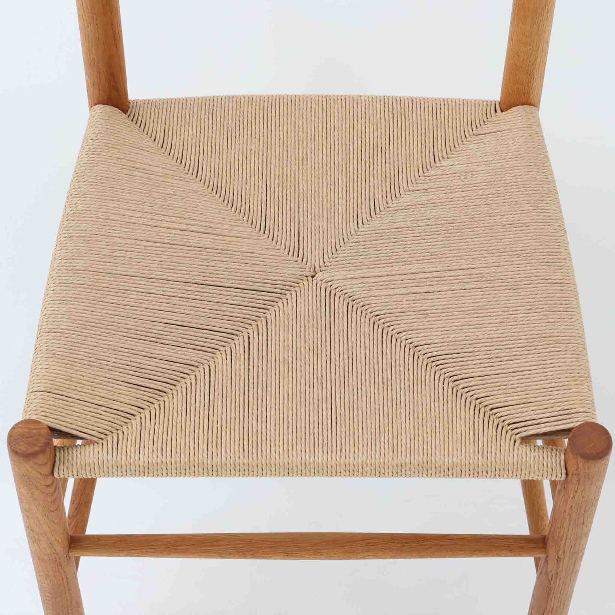 デンマークを代表するデザイナー、Borge MogensenによってFDBのためにデザインされたJ39チェアは、オーク材の丸脚と座面に丁寧に編み込まれたペーパーコードが特徴の、素朴ながらも完成度の高い北欧ビンテージチェアです。農村のキッチンチェアをルーツに持つそのデザインは、無駄を省いた潔い構造と機能美が融合し、空間に凛とした佇まいをもたらします。ダイニングはもちろん、ワークチェアやアクセントチェアとしても重宝する一脚です。