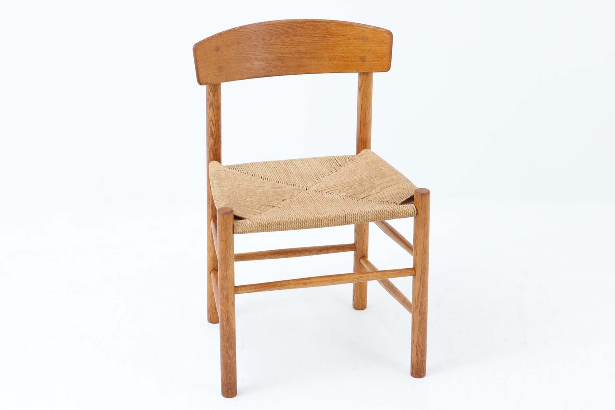 こちらは、1956年にデザインされたJ39チェアです。そのシンプルで頑丈なデザインは広く知られ、「The People's Chair（人々の椅子）」としても愛されています。現在はFredericia社から販売されていますが、こちらは初期のFDB mobler社製の貴重なモデルです。クリーニングのみ行った状態で、経年により色味が深みを増したオーク材のフレームが魅力的です。ビンテージ感をお楽しみいただける状態でお手頃価格でご提供しています。