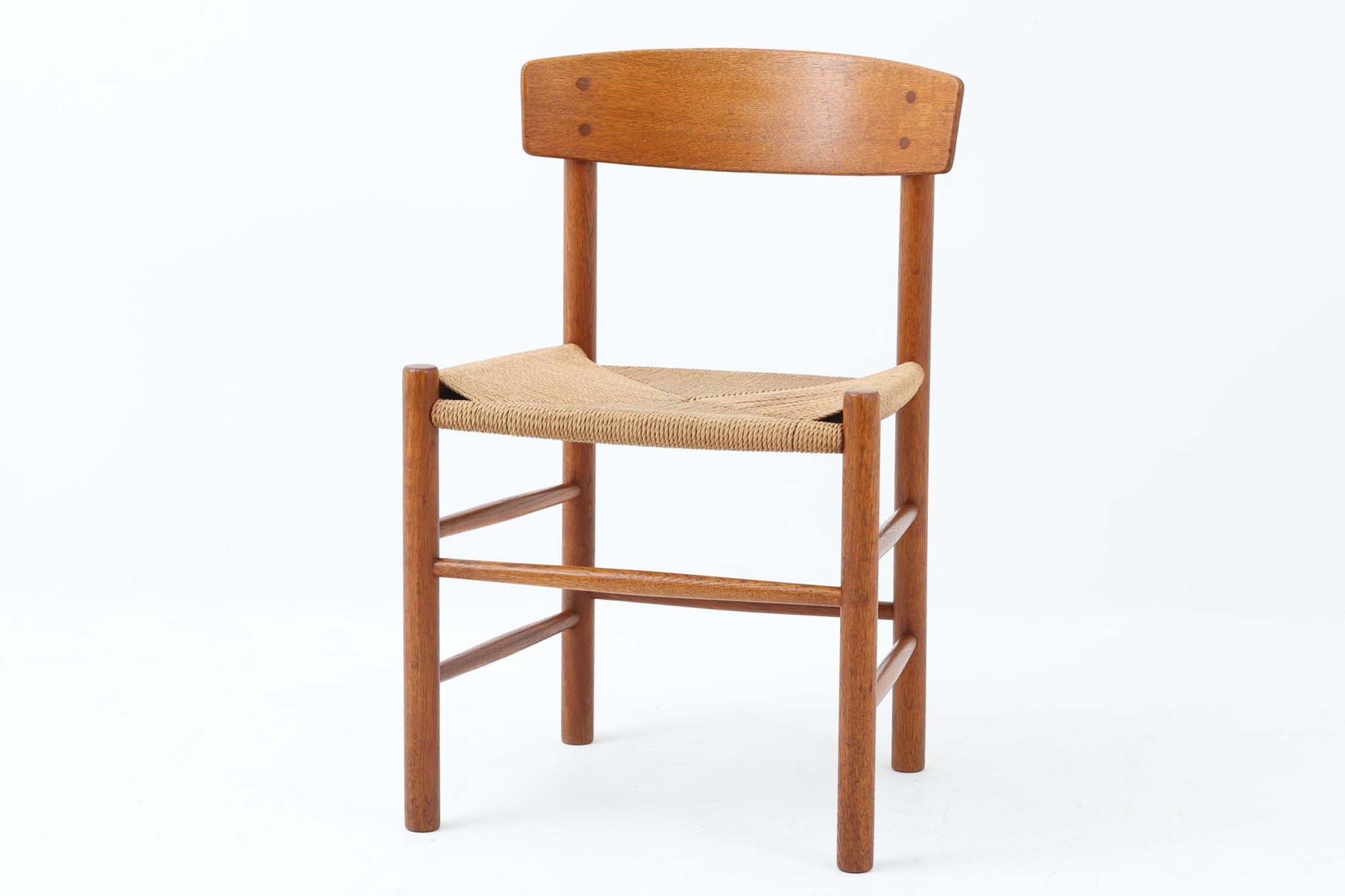 こちらは、1956年にデザインされたJ39チェアです。そのシンプルで頑丈なデザインは広く知られ、「The People's Chair（人々の椅子）」としても愛されています。現在はFredericia社から販売されていますが、こちらは初期のFDB mobler社製の貴重なモデルです。クリーニングのみ行った状態で、経年により色味が深みを増したオーク材のフレームが魅力的です。ビンテージ感をお楽しみいただける状態でお手頃価格でご提供しています。