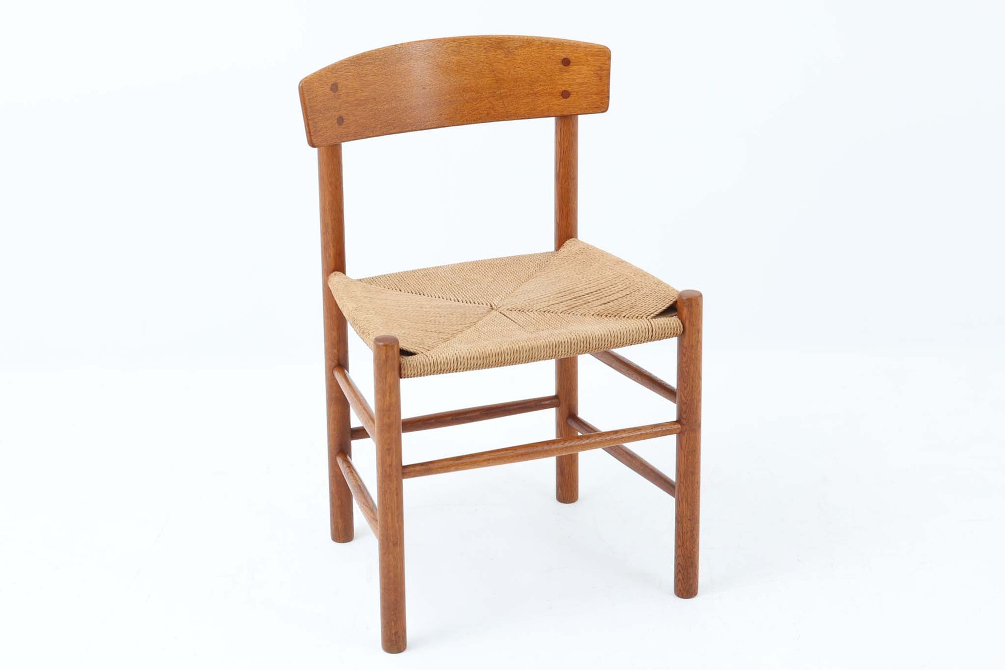 こちらは、1956年にデザインされたJ39チェアです。そのシンプルで頑丈なデザインは広く知られ、「The People's Chair（人々の椅子）」としても愛されています。現在はFredericia社から販売されていますが、こちらは初期のFDB mobler社製の貴重なモデルです。クリーニングのみ行った状態で、経年により色味が深みを増したオーク材のフレームが魅力的です。ビンテージ感をお楽しみいただける状態でお手頃価格でご提供しています。