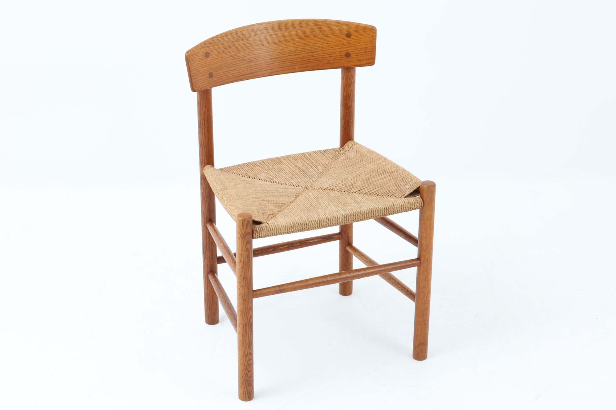 こちらは、1956年にデザインされたJ39チェアです。そのシンプルで頑丈なデザインは広く知られ、「The People's Chair（人々の椅子）」としても愛されています。現在はFredericia社から販売されていますが、こちらは初期のFDB mobler社製の貴重なモデルです。クリーニングのみ行った状態で、経年により色味が深みを増したオーク材のフレームが魅力的です。ビンテージ感をお楽しみいただける状態でお手頃価格でご提供しています。