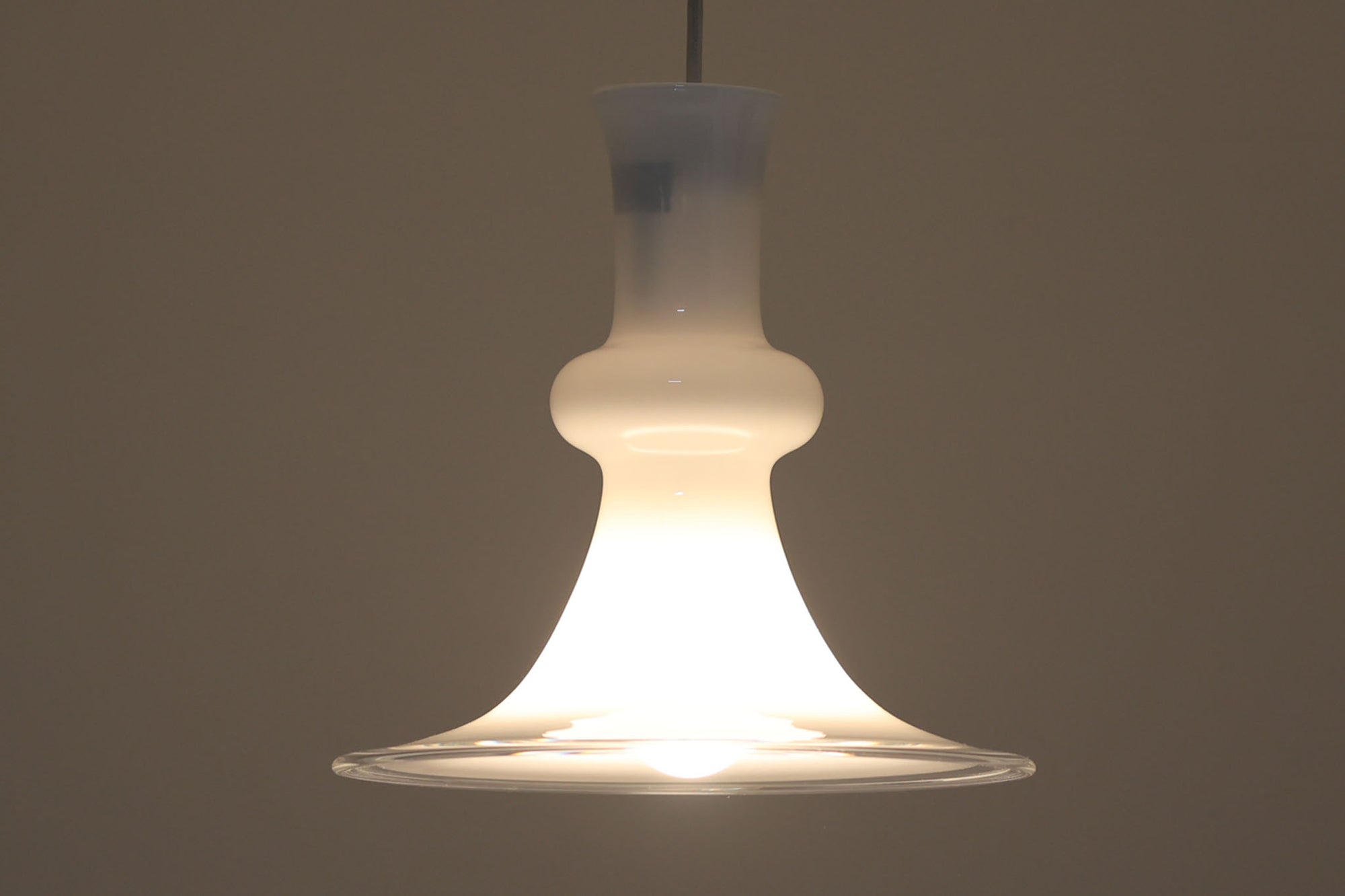 北欧より買い付けた、ホルムガード社製(現Royal Copenhagen)ビンテージランプです。ガラス製のペンダントライト「Etude Pendel」。クラシカルな曲線が美しいフォルムと、乳白色のガラスシェードが柔らかな光を拡げ、空間に優しい印象を与えてくれます。シェード下部はクリアガラスになっており、下方向への光をしっかり届けながらも、グラデーションのような光の演出が楽しめます。直径約28cmと使いやすいサイズで、ダイニングや玄関、ベッドサイドなど多様なシーンで活躍します。エレガントで品のある北欧照明をお探しの方におすすめの一灯です。