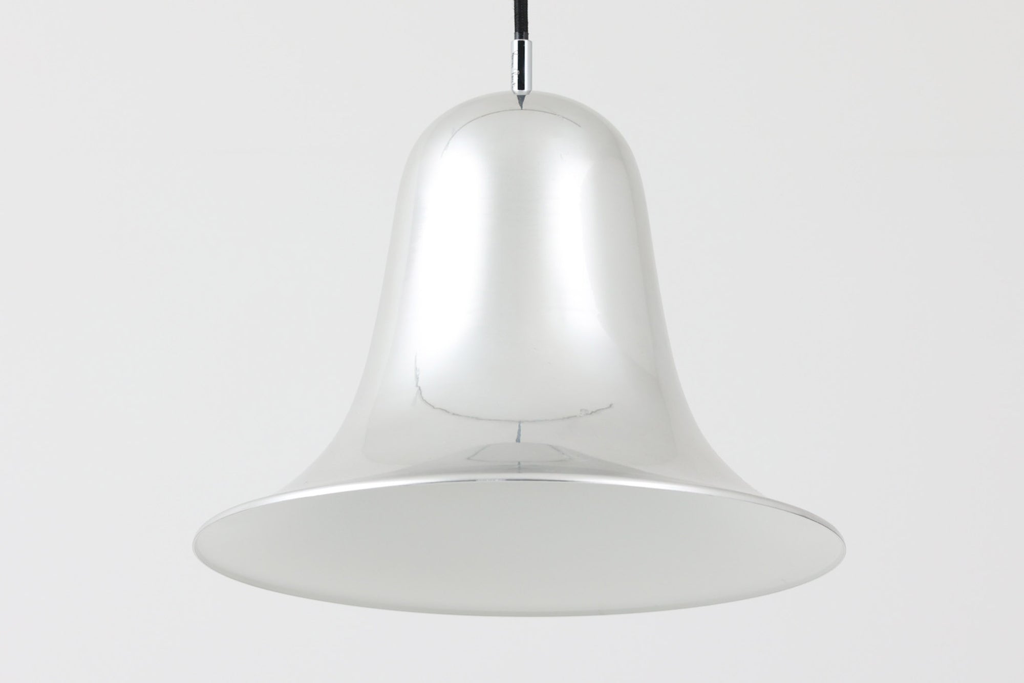 デンマークを代表する照明デザイナーVerner Panton（バーナー・パントン）が手がけた、Frandsen Lighting（フランセン・ライティング）社製のペンダントライトです。なだらかな曲線を描くベル型のシルエットに、ミラーのように周囲を映し出すクローム仕上げが施された、存在感のある一灯。直径約30cmと比較的大ぶりなサイズ感で、1灯でも空間のアクセントとなり、テーブル上や吹き抜け空間などにも映えます。内側はホワイトに塗装されており、点灯時には光を柔らかく広げながらもしっかりとした明るさを確保。Frandsen Lighting社はかつてVerner Pantonとのライセンス契約を結び、このモデルを製造していましたが、現在ではその契約も終了しており、本品のようなオリジナルはヴィンテージ品でしか手に入らなくなっています。特に直径30cmの大きなサイズは現行品では展開されておらず、希少性の高いアイテムとなっています。