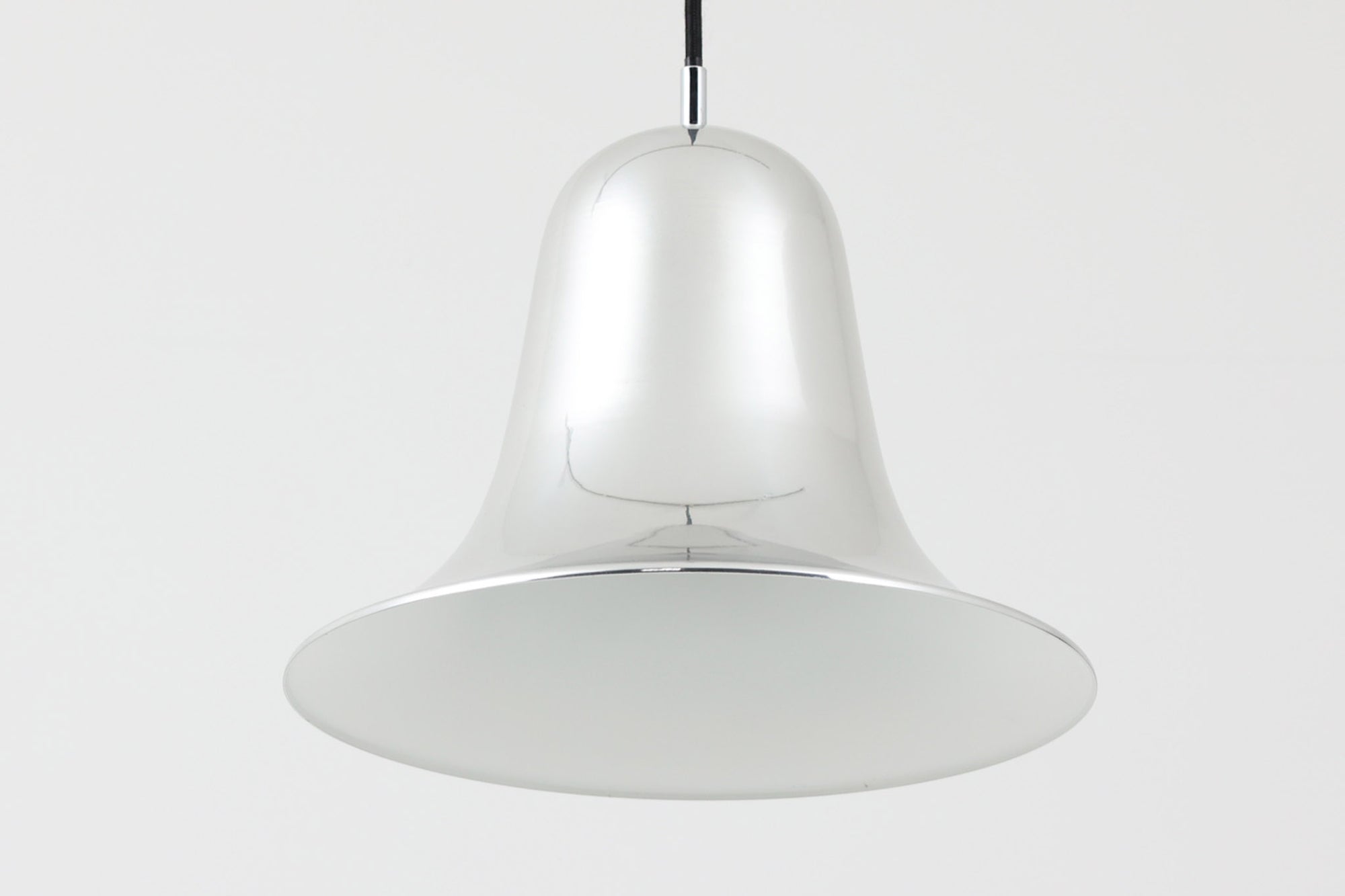 デンマークを代表する照明デザイナーVerner Panton（バーナー・パントン）が手がけた、Frandsen Lighting（フランセン・ライティング）社製のペンダントライトです。なだらかな曲線を描くベル型のシルエットに、ミラーのように周囲を映し出すクローム仕上げが施された、存在感のある一灯。直径約30cmと比較的大ぶりなサイズ感で、1灯でも空間のアクセントとなり、テーブル上や吹き抜け空間などにも映えます。内側はホワイトに塗装されており、点灯時には光を柔らかく広げながらもしっかりとした明るさを確保。Frandsen Lighting社はかつてVerner Pantonとのライセンス契約を結び、このモデルを製造していましたが、現在ではその契約も終了しており、本品のようなオリジナルはヴィンテージ品でしか手に入らなくなっています。特に直径30cmの大きなサイズは現行品では展開されておらず、希少性の高いアイテムとなっています。