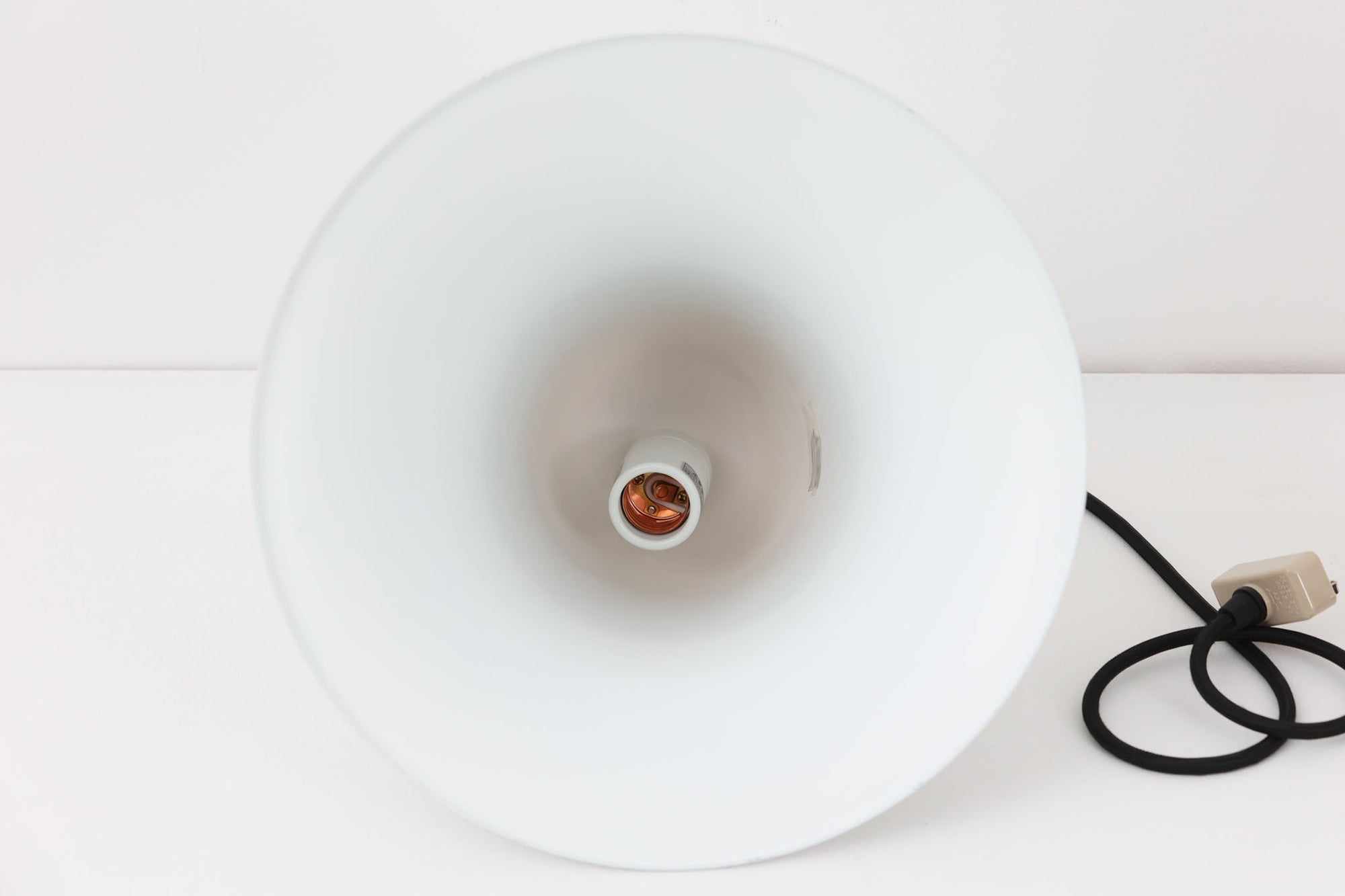 デンマークを代表する照明デザイナーVerner Panton（バーナー・パントン）が手がけた、Frandsen Lighting（フランセン・ライティング）社製のペンダントライトです。なだらかな曲線を描くベル型のシルエットに、ミラーのように周囲を映し出すクローム仕上げが施された、存在感のある一灯。直径約30cmと比較的大ぶりなサイズ感で、1灯でも空間のアクセントとなり、テーブル上や吹き抜け空間などにも映えます。内側はホワイトに塗装されており、点灯時には光を柔らかく広げながらもしっかりとした明るさを確保。Frandsen Lighting社はかつてVerner Pantonとのライセンス契約を結び、このモデルを製造していましたが、現在ではその契約も終了しており、本品のようなオリジナルはヴィンテージ品でしか手に入らなくなっています。特に直径30cmの大きなサイズは現行品では展開されておらず、希少性の高いアイテムとなっています。