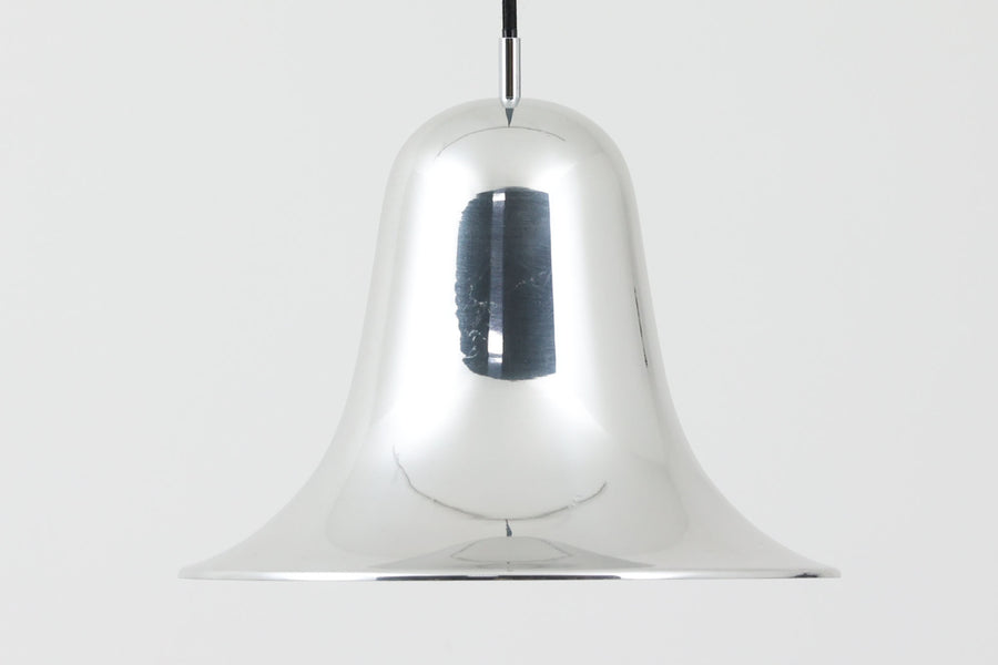 デンマークを代表する照明デザイナーVerner Panton（バーナー・パントン）が手がけた、Frandsen Lighting（フランセン・ライティング）社製のペンダントライトです。なだらかな曲線を描くベル型のシルエットに、ミラーのように周囲を映し出すクローム仕上げが施された、存在感のある一灯。直径約30cmと比較的大ぶりなサイズ感で、1灯でも空間のアクセントとなり、テーブル上や吹き抜け空間などにも映えます。内側はホワイトに塗装されており、点灯時には光を柔らかく広げながらもしっかりとした明るさを確保。Frandsen Lighting社はかつてVerner Pantonとのライセンス契約を結び、このモデルを製造していましたが、現在ではその契約も終了しており、本品のようなオリジナルはヴィンテージ品でしか手に入らなくなっています。特に直径30cmの大きなサイズは現行品では展開されておらず、希少性の高いアイテムとなっています。