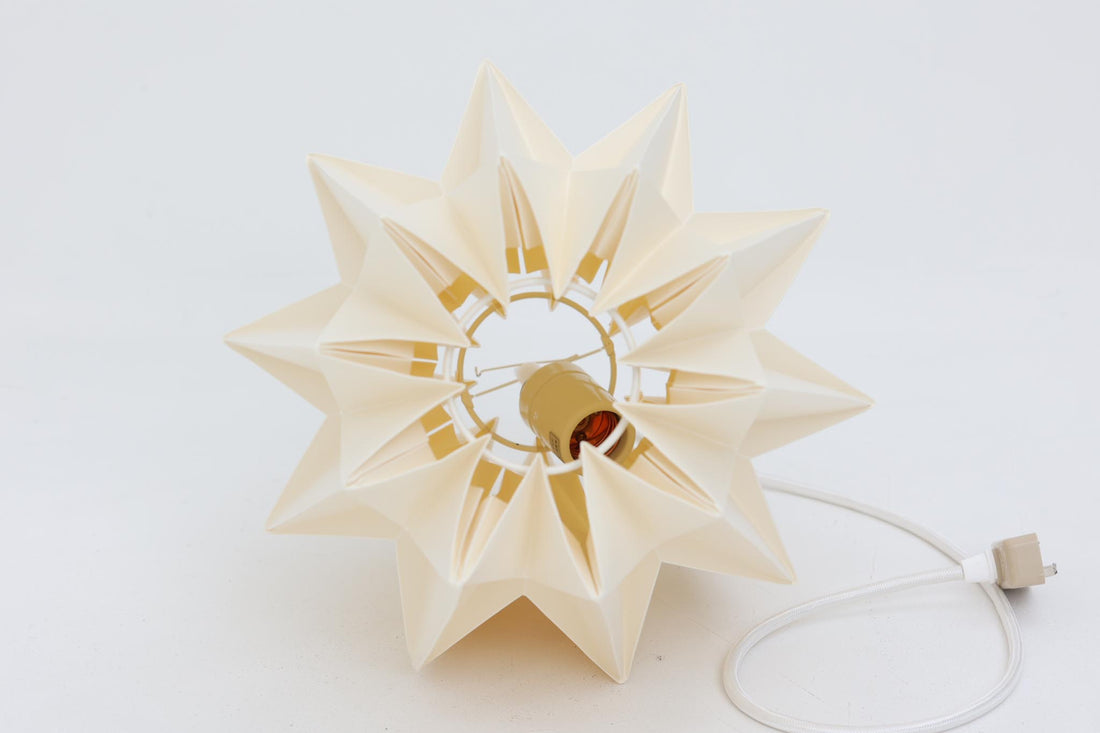 デンマークの名門Le Klintによるmodel 152。Peter Hvidt & Orla mølgaard Nielsenによってデザインされたこのモデルは、手折りのプリーツシェードによって生まれる立体的な陰影が魅力。点灯時には柔らかく温かみのある光を放ち、消灯時もアートピースのような存在感を放ちます。シェードには経年による軽微な変色や小さな折れが見られますが、全体として美しいフォルムと機能性を兼ね備えています。直径約27cmで、玄関やダイニング、ベッドサイドにもおすすめのサイズです。