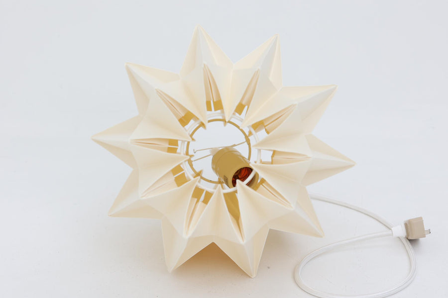 デンマークの名門Le Klintによるmodel 152。Peter Hvidt & Orla mølgaard Nielsenによってデザインされたこのモデルは、手折りのプリーツシェードによって生まれる立体的な陰影が魅力。点灯時には柔らかく温かみのある光を放ち、消灯時もアートピースのような存在感を放ちます。シェードには経年による軽微な変色や小さな折れが見られますが、全体として美しいフォルムと機能性を兼ね備えています。直径約27cmで、玄関やダイニング、ベッドサイドにもおすすめのサイズです。