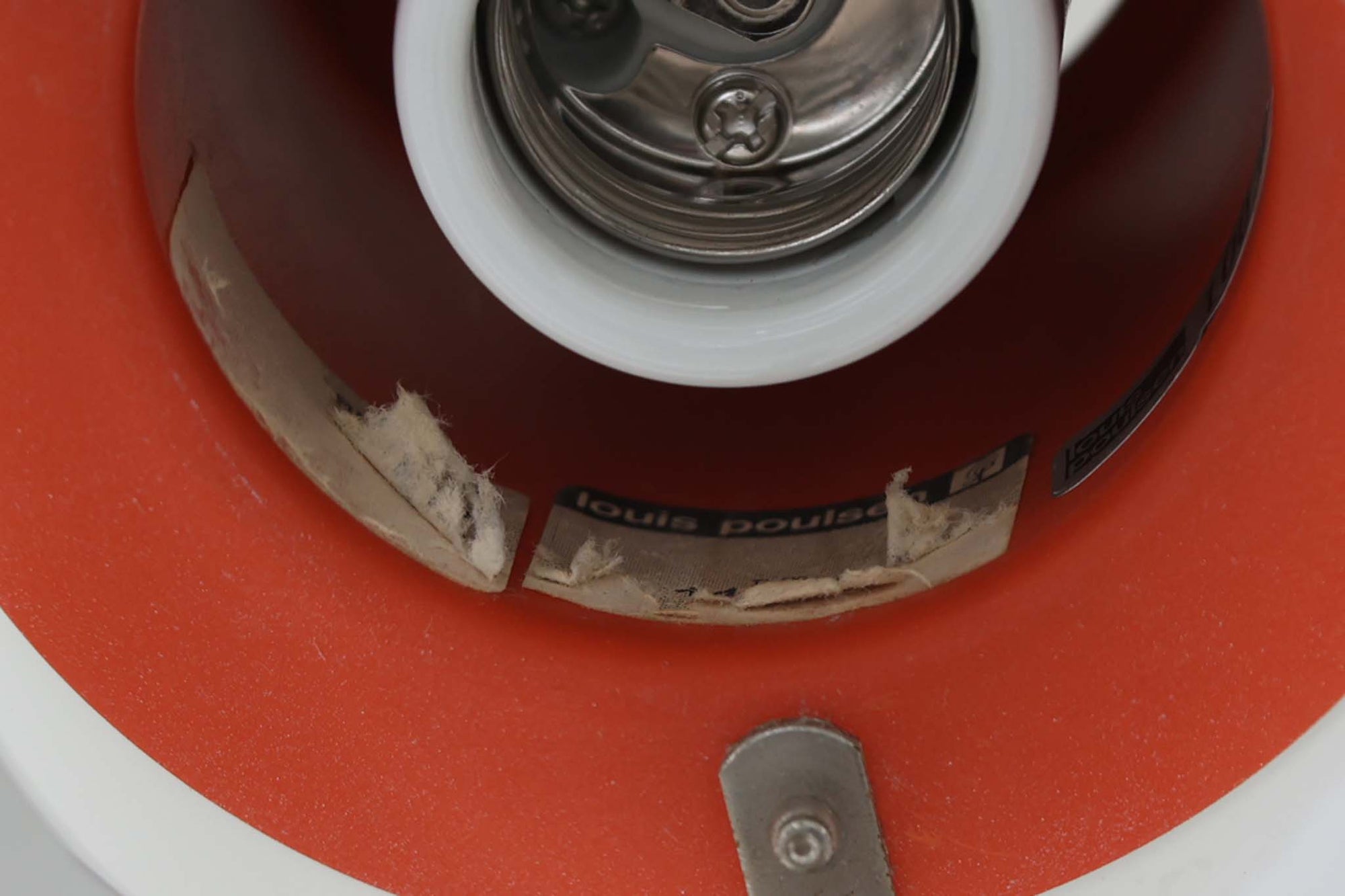 北欧照明の巨匠Poul Henningsenによってデザインされた「PH4」ペンダントライト。Louis Poulsen社製で、光を効率よく拡散させる3枚シェード構造が特徴。内側にオレンジのリフレクターを備えており、暖かく落ち着いた光を演出します。シェード表面には経年に伴う擦れや細かい傷、塗装の薄れが見られますが、ビンテージらしい味わいを感じられる一品です。リビングやダイニング、カウンター上などにおすすめのサイズ感です。