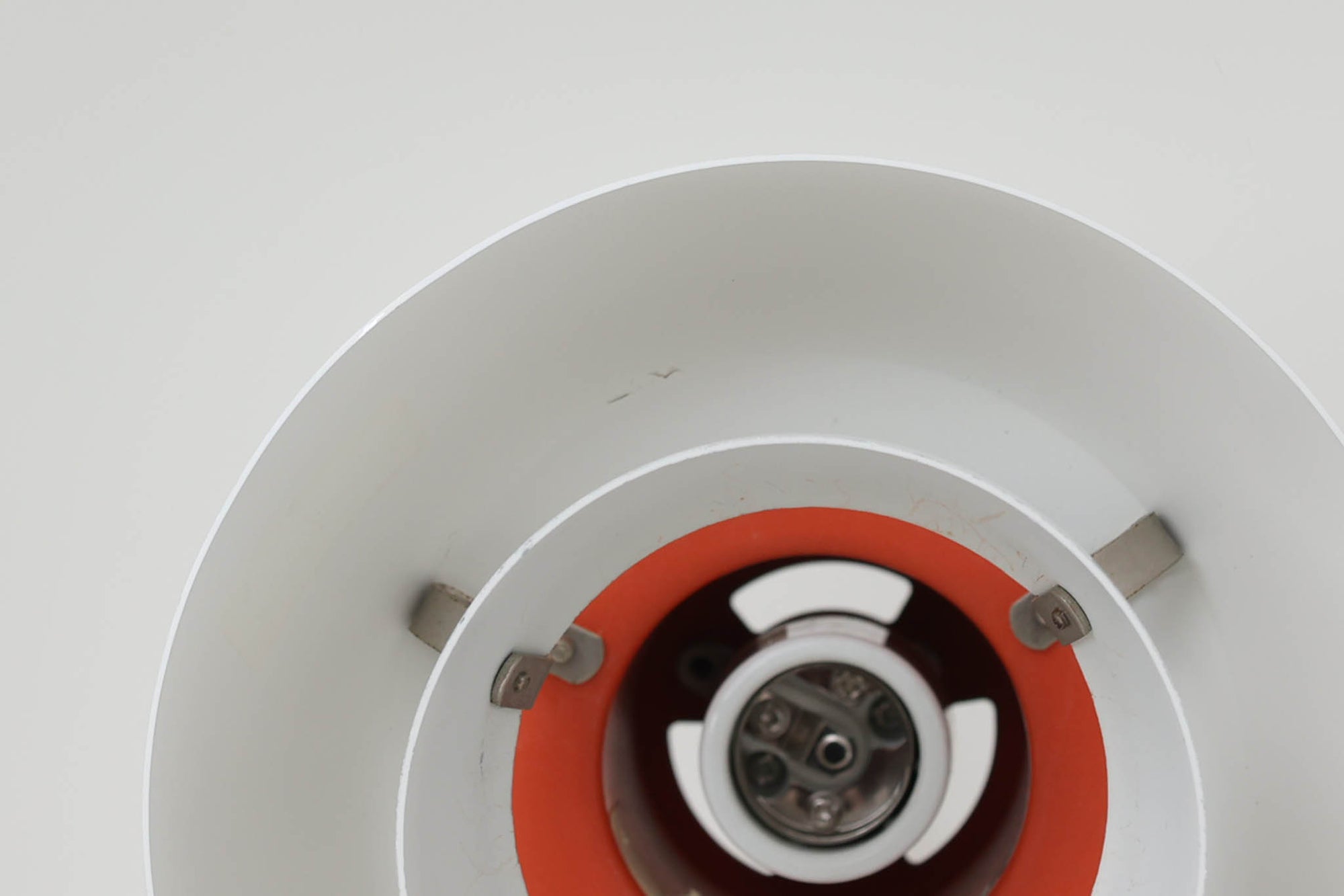 北欧照明の巨匠Poul Henningsenによってデザインされた「PH4」ペンダントライト。Louis Poulsen社製で、光を効率よく拡散させる3枚シェード構造が特徴。内側にオレンジのリフレクターを備えており、暖かく落ち着いた光を演出します。シェード表面には経年に伴う擦れや細かい傷、塗装の薄れが見られますが、ビンテージらしい味わいを感じられる一品です。リビングやダイニング、カウンター上などにおすすめのサイズ感です。