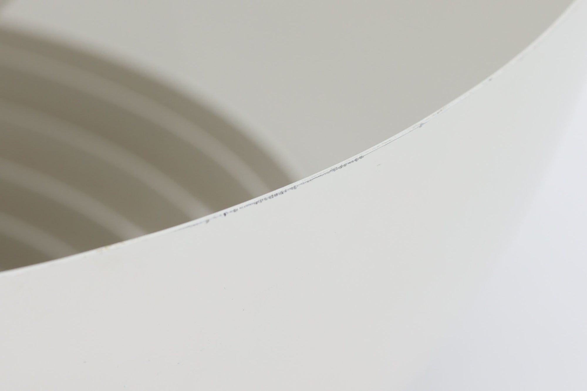 デンマークを代表する建築家・デザイナー、アルネ・ヤコブセンによってデザインされた「AJロイヤル」ペンダントライト。Louis Poulsen（ルイスポールセン）社より発表され、建築物と調和するミニマルなフォルムが特徴的です。こちらは直径50cmのホワイトカラーのモデルで、1958年に設計されたコペンハーゲンのSASロイヤルホテルのために開発されたシリーズのひとつ。上部のルーバー構造からも光が漏れる設計により、下方向だけでなく柔らかく空間全体を照らします。モダニズムの美学が息づく名作照明でありながら、日常の空間にもすっと馴染む柔らかな存在感が魅力です。ヴィンテージ品のため、シェードには擦り傷や小さな塗装剥がれ、内側に若干のサビが見られますが、使用には問題ありません。全体としては良好なコンディションを保っており、ヴィンテージならではの風合いをお楽しみいただけます。コードおよびソケットは国内基準に適合した仕様に交換済みで、すぐにご使用いただけます。