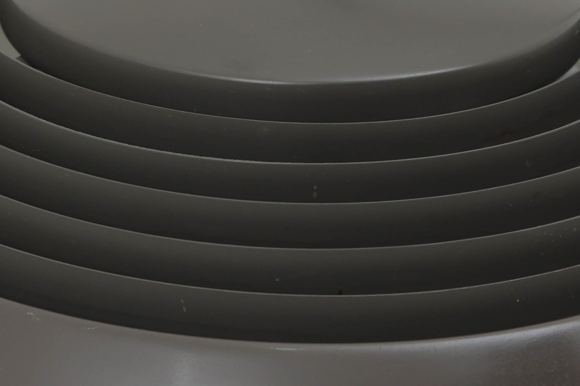 アルネ・ヤコブセンによってデザインされ、Louis Poulsen（ルイスポールセン）より製造されたAJロイヤル ペンダントライト。こちらは希少なグラファイトグレーカラーで、落ち着いたトーンが空間にシックな雰囲気を演出します。直径50cmの大型サイズで、光源を遮る構造と放射状に配置されたルーバーにより、眩しさを抑えた柔らかい光が空間全体を包み込みます。点灯時には上部のスリットから漏れる光も美しく、デザイン性と機能性を兼ね備えた一品です。外観には小傷や使用感がありますが、ビンテージならではの風合いとしてお楽しみいただけます。