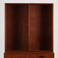 チーク材を使用したスウェーデン製のディスプレイシェルフです。上段は収納力のある可動棚付きのオープンスペース、下段には引き出し4杯と扉収納が備えられており、実用性とデザイン性を兼ね備えた構成です。シンプルな取手の意匠や直線的な脚部が北欧家具らしい洗練を感じさせ、経年により深みを増したチークの色合いが空間に温かみを与えます。リビングや書斎での本や雑貨の収納・展示におすすめのビンテージアイテムです。