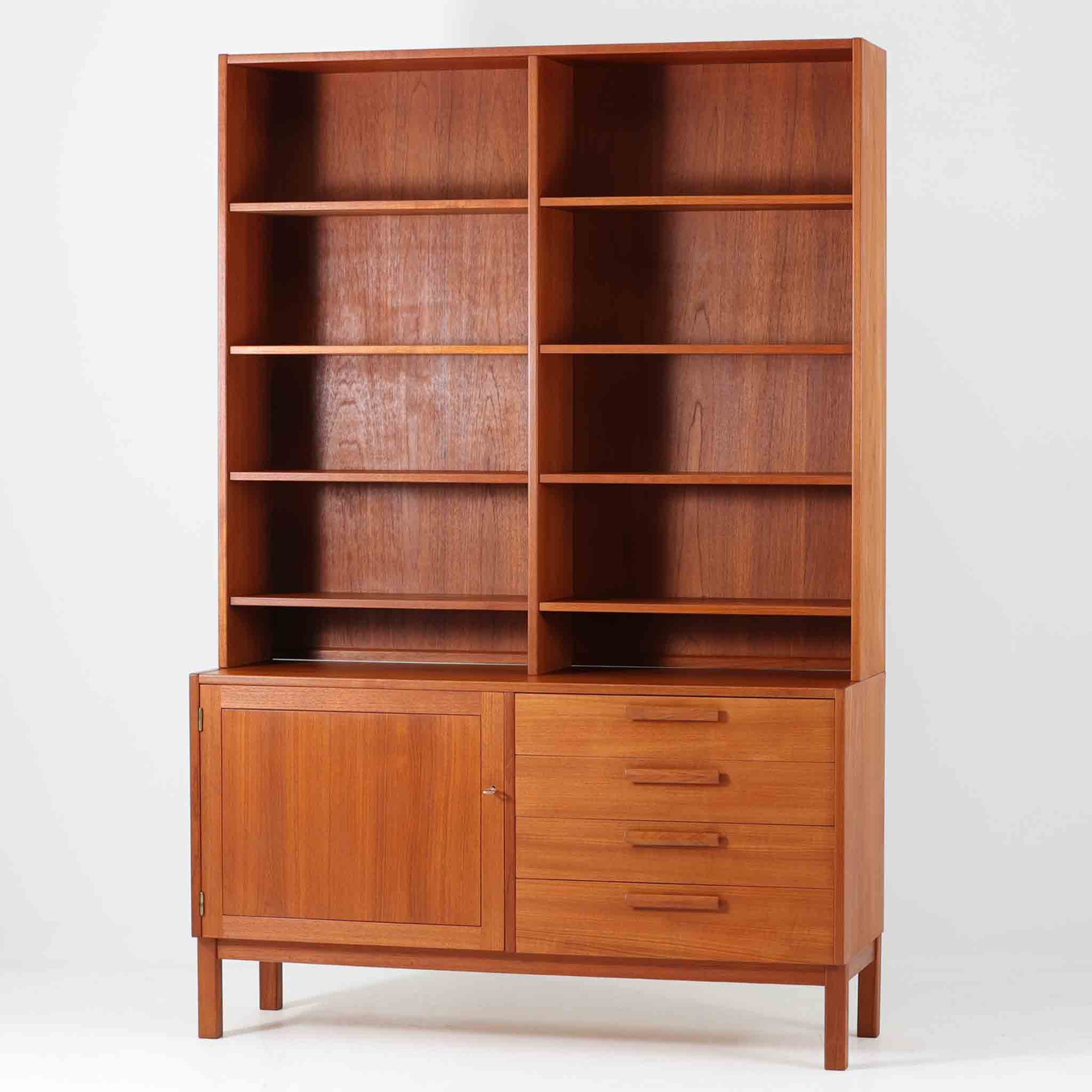 Nils JonssonがTroeds社のためにデザインした「Domi Monté」モデルのディスプレイシェルフ。チーク材を贅沢に使用し、温かみのある木肌と洗練されたフォルムが魅力の一台です。上部には高さ調整が可能な可動棚が8枚備わり、本やオブジェのディスプレイに柔軟に対応。下部には扉付き収納と仕切り付きの引き出しが配されており、実用性にも優れます。背面にはTroeds社の刻印が残されており、スウェーデン製ビンテージ家具としての確かな出自を物語ります。空間に落ち着きと上質な雰囲気を添える、北欧モダンらしい逸品です。