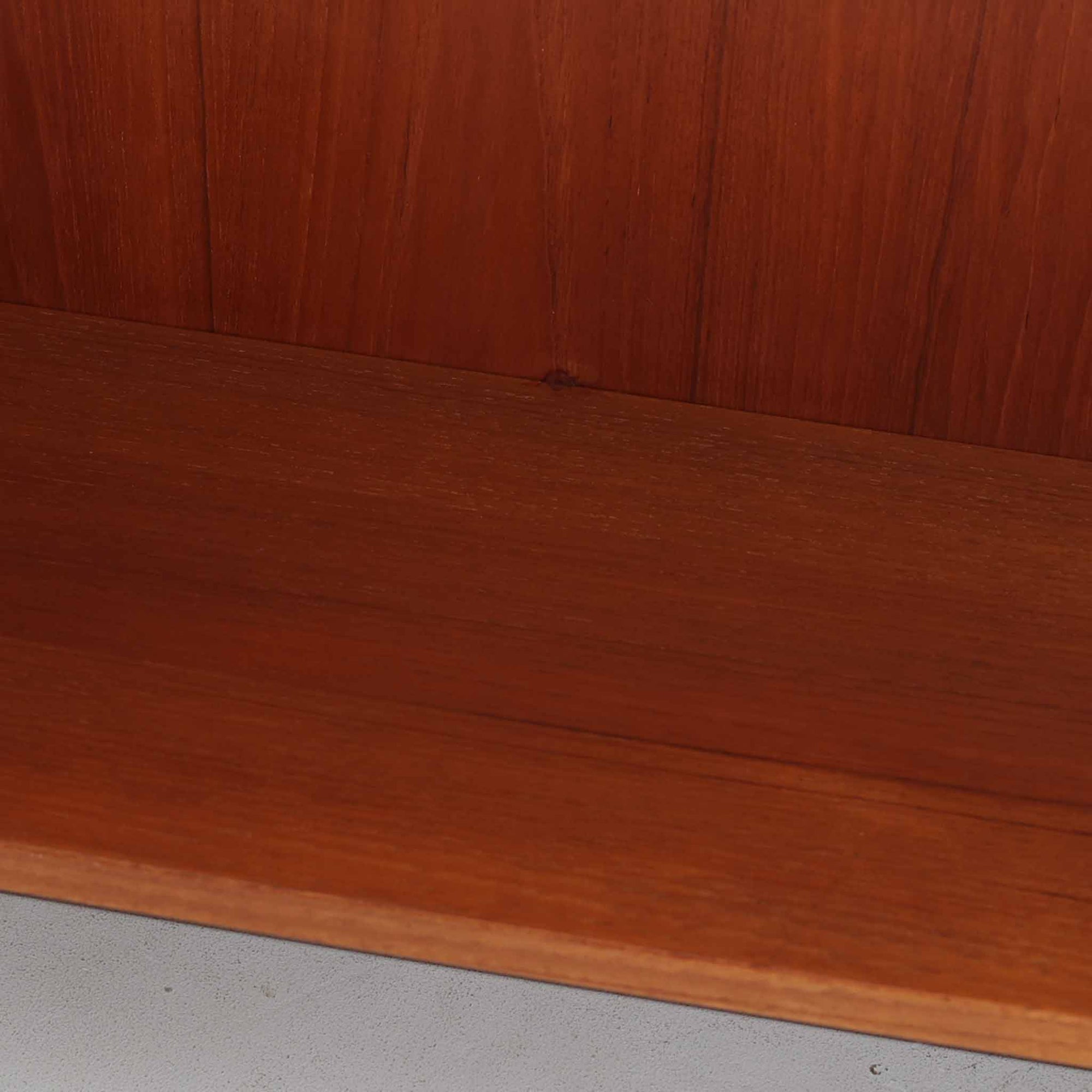 Nils JonssonがTroeds社のためにデザインした「Domi Monté」モデルのディスプレイシェルフ。チーク材を贅沢に使用し、温かみのある木肌と洗練されたフォルムが魅力の一台です。上部には高さ調整が可能な可動棚が8枚備わり、本やオブジェのディスプレイに柔軟に対応。下部には扉付き収納と仕切り付きの引き出しが配されており、実用性にも優れます。背面にはTroeds社の刻印が残されており、スウェーデン製ビンテージ家具としての確かな出自を物語ります。空間に落ち着きと上質な雰囲気を添える、北欧モダンらしい逸品です。