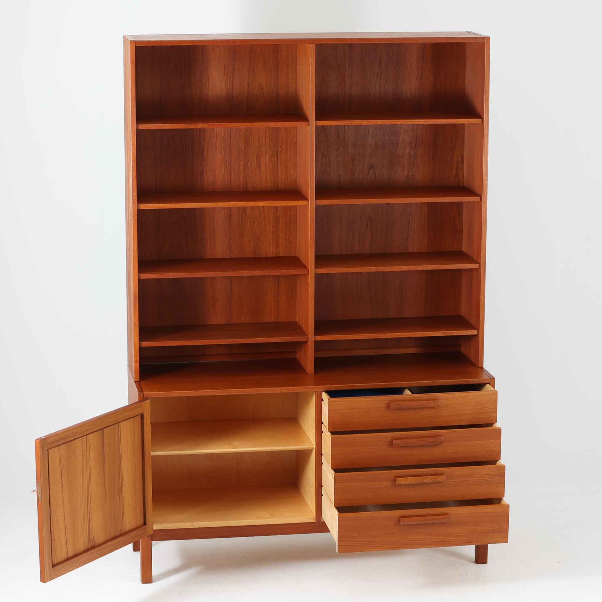 Nils JonssonがTroeds社のためにデザインした「Domi Monté」モデルのディスプレイシェルフ。チーク材を贅沢に使用し、温かみのある木肌と洗練されたフォルムが魅力の一台です。上部には高さ調整が可能な可動棚が8枚備わり、本やオブジェのディスプレイに柔軟に対応。下部には扉付き収納と仕切り付きの引き出しが配されており、実用性にも優れます。背面にはTroeds社の刻印が残されており、スウェーデン製ビンテージ家具としての確かな出自を物語ります。空間に落ち着きと上質な雰囲気を添える、北欧モダンらしい逸品です。