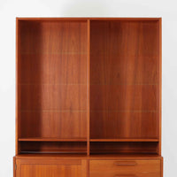 Nils JonssonがTroeds社のためにデザインした「Domi Monté」モデルのディスプレイシェルフ。チーク材を贅沢に使用し、温かみのある木肌と洗練されたフォルムが魅力の一台です。上部には高さ調整が可能な可動棚が8枚備わり、本やオブジェのディスプレイに柔軟に対応。下部には扉付き収納と仕切り付きの引き出しが配されており、実用性にも優れます。背面にはTroeds社の刻印が残されており、スウェーデン製ビンテージ家具としての確かな出自を物語ります。空間に落ち着きと上質な雰囲気を添える、北欧モダンらしい逸品です。