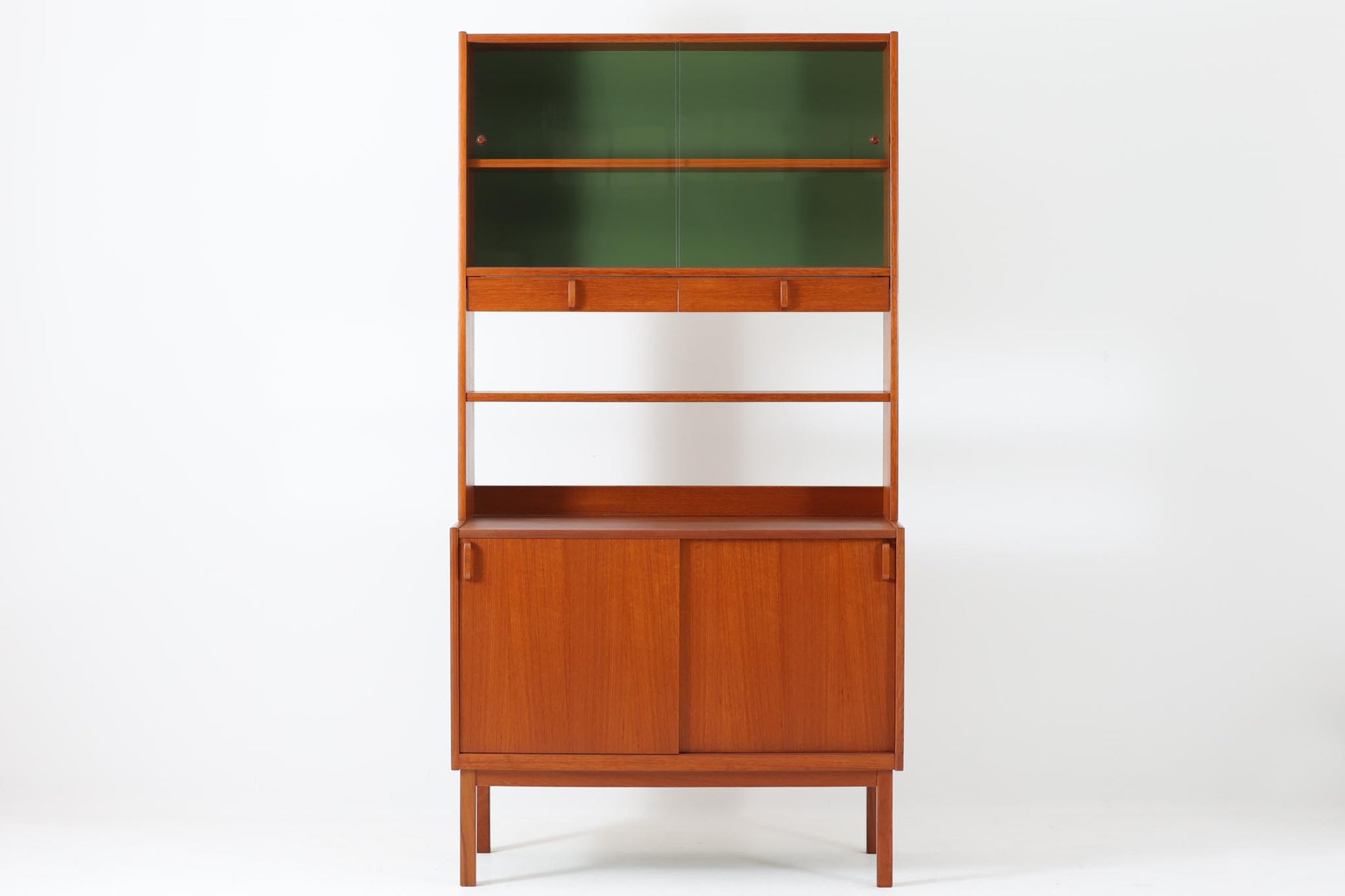 スウェーデンの老舗家具メーカーBodafors社によって製造されたヴィンテージのディスプレイシェルフ。デザインを手がけたのはスウェーデンのデザイナー、Bertil Fridhagen。上部はスライド式のガラス扉と引き出し収納を備え、下部にはチーク材のスライド扉を組み合わせた実用性の高い構成です。グリーンの背板がアクセントとなり、飾るものを引き立てながら、空間に柔らかな彩りを添えます。細部のディテールにも北欧らしい丁寧な作り込みが感じられ、使い勝手と美しさが調和した一台。リビングでのディスプレイ収納としてはもちろん、食器棚や書棚など多目的に活躍します。