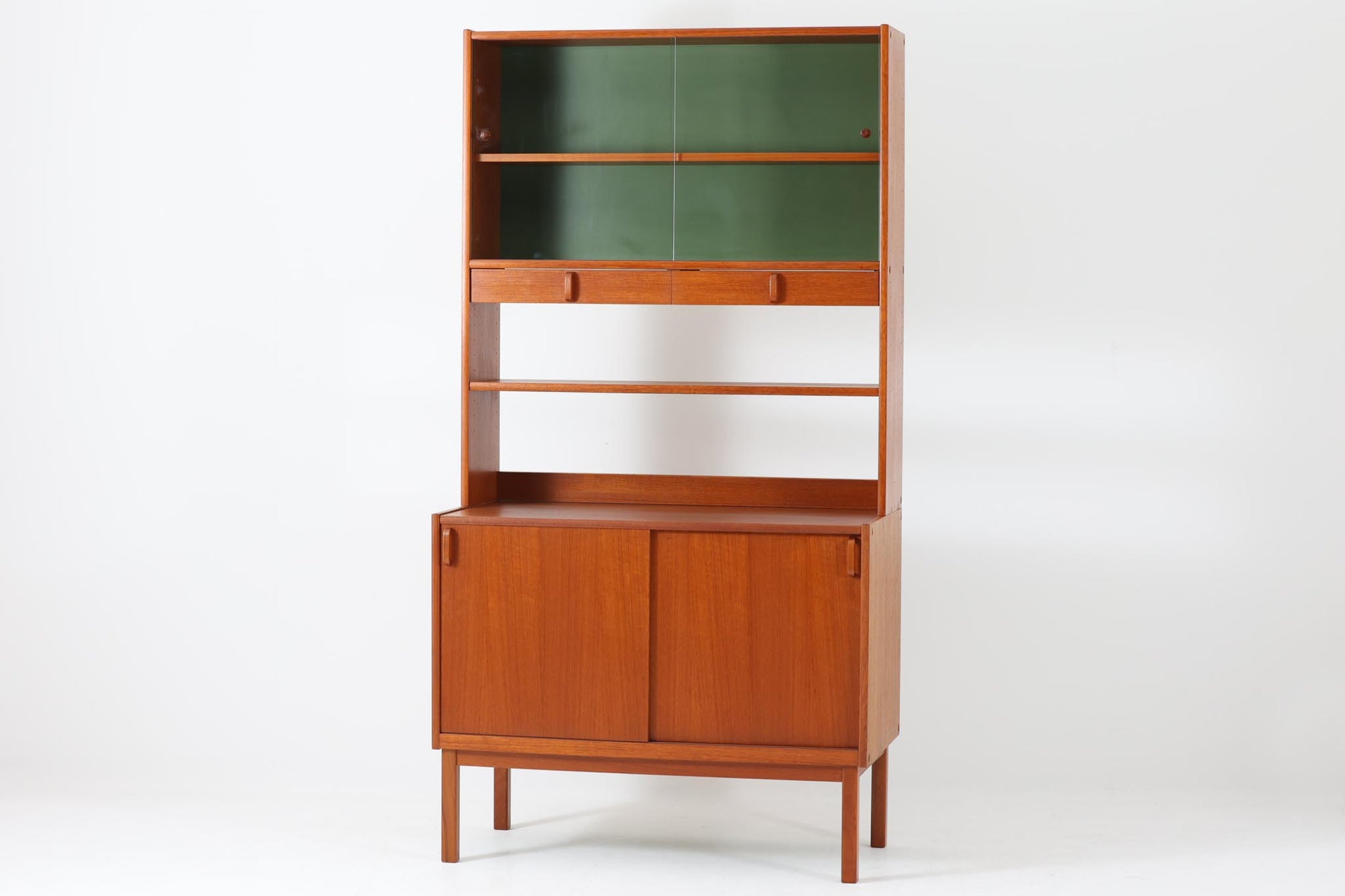 スウェーデンの老舗家具メーカーBodafors社によって製造されたヴィンテージのディスプレイシェルフ。デザインを手がけたのはスウェーデンのデザイナー、Bertil Fridhagen。上部はスライド式のガラス扉と引き出し収納を備え、下部にはチーク材のスライド扉を組み合わせた実用性の高い構成です。グリーンの背板がアクセントとなり、飾るものを引き立てながら、空間に柔らかな彩りを添えます。細部のディテールにも北欧らしい丁寧な作り込みが感じられ、使い勝手と美しさが調和した一台。リビングでのディスプレイ収納としてはもちろん、食器棚や書棚など多目的に活躍します。