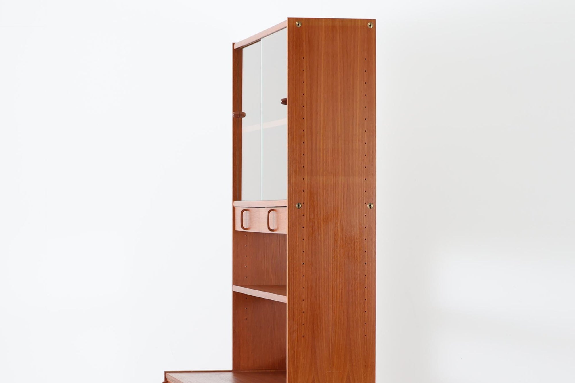 スウェーデンの老舗家具メーカーBodafors社によって製造されたヴィンテージのディスプレイシェルフ。デザインを手がけたのはスウェーデンのデザイナー、Bertil Fridhagen。上部はスライド式のガラス扉と引き出し収納を備え、下部にはチーク材のスライド扉を組み合わせた実用性の高い構成です。グリーンの背板がアクセントとなり、飾るものを引き立てながら、空間に柔らかな彩りを添えます。細部のディテールにも北欧らしい丁寧な作り込みが感じられ、使い勝手と美しさが調和した一台。リビングでのディスプレイ収納としてはもちろん、食器棚や書棚など多目的に活躍します。