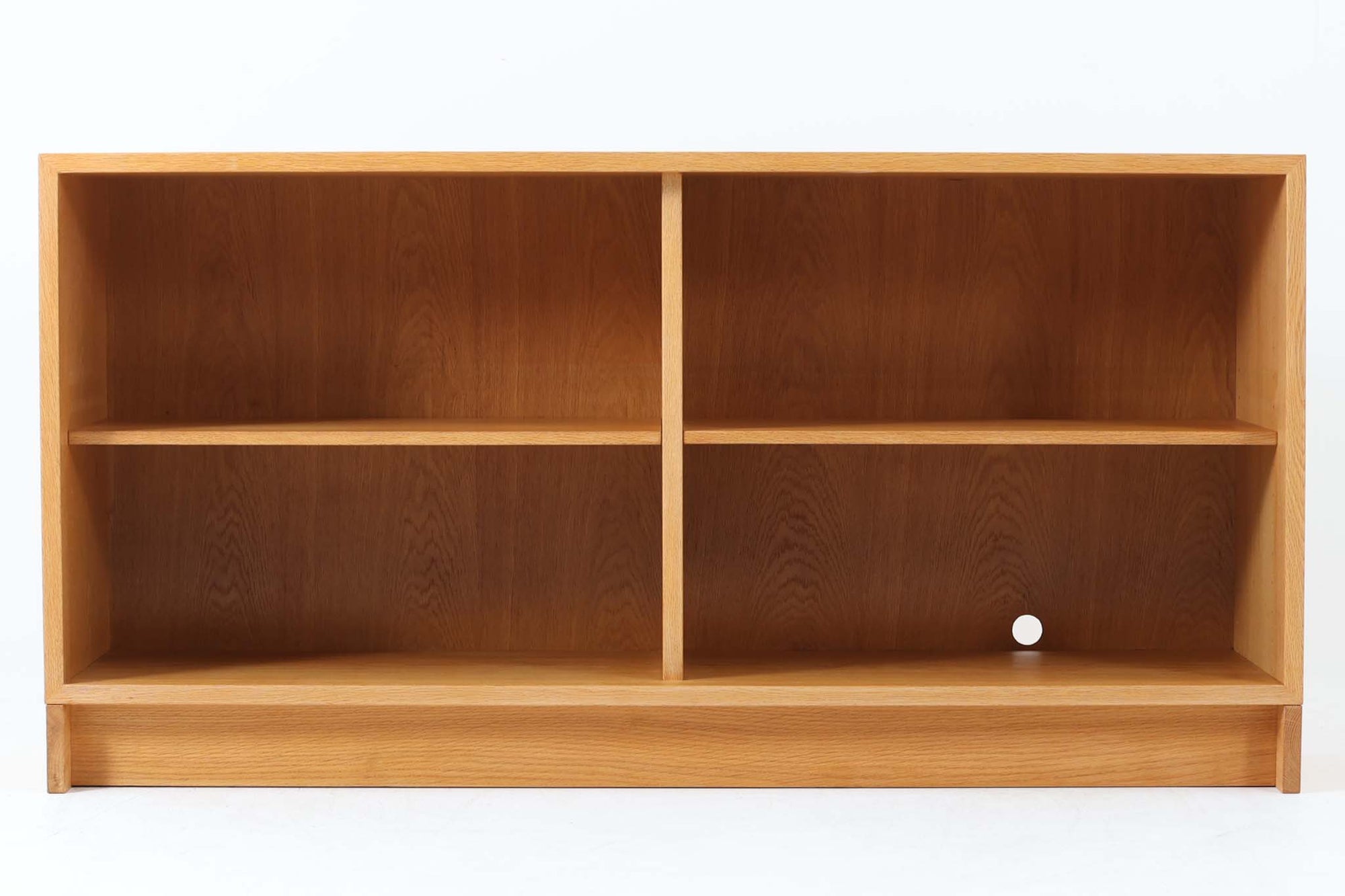 デンマークを代表するデザイナー、Børge mogensen（ボーエ・モーエンセン）によってデザインされた、Karl Andersson（カール・アンダーソン）社製のスモールブックシェルフです。素材には、美しい木目と優れた耐久性を兼ね備えたオーク材を使用しており、ナチュラルで温かみのある佇まいが魅力です。幅134cmと程よいサイズ感で、リビングや書斎、子ども部屋など、さまざまな空間に取り入れやすい仕様となっています。シンプルな構造の中に、モーエンセンらしい実用性と機能美が凝縮されており、背面には配線用の穴も設けられているため、テレビ台やAVボードとしての使用も可能です。実際に前オーナーもAVボードとして使用していた形跡があり、汎用性の高さも魅力のひとつ。北欧デザインの真髄を感じられる、実用性と美しさを兼ね備えた一台です。