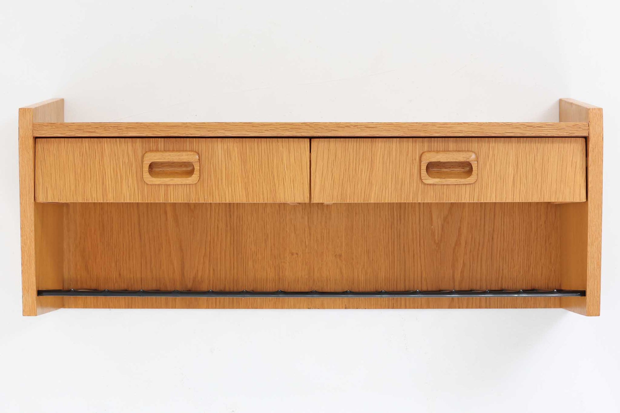 スウェーデン製のヴィンテージウォールシェルフ。素材には木目の美しいオーク材を使用し、下部にはスチール製のバーがあしらわれた、実用性とデザイン性を兼ね備えた一台です。緩やかに角度のついたサイドパネルが印象的で、北欧らしいモダンな佇まいを見せてくれます。2杯の引き出しは小物収納に便利で、下段のバーにはストールや雑誌などを置く事も可能。玄関やリビング、キッチンなどさまざまな空間で活躍する、機能的で美しいウォールシェルフです。