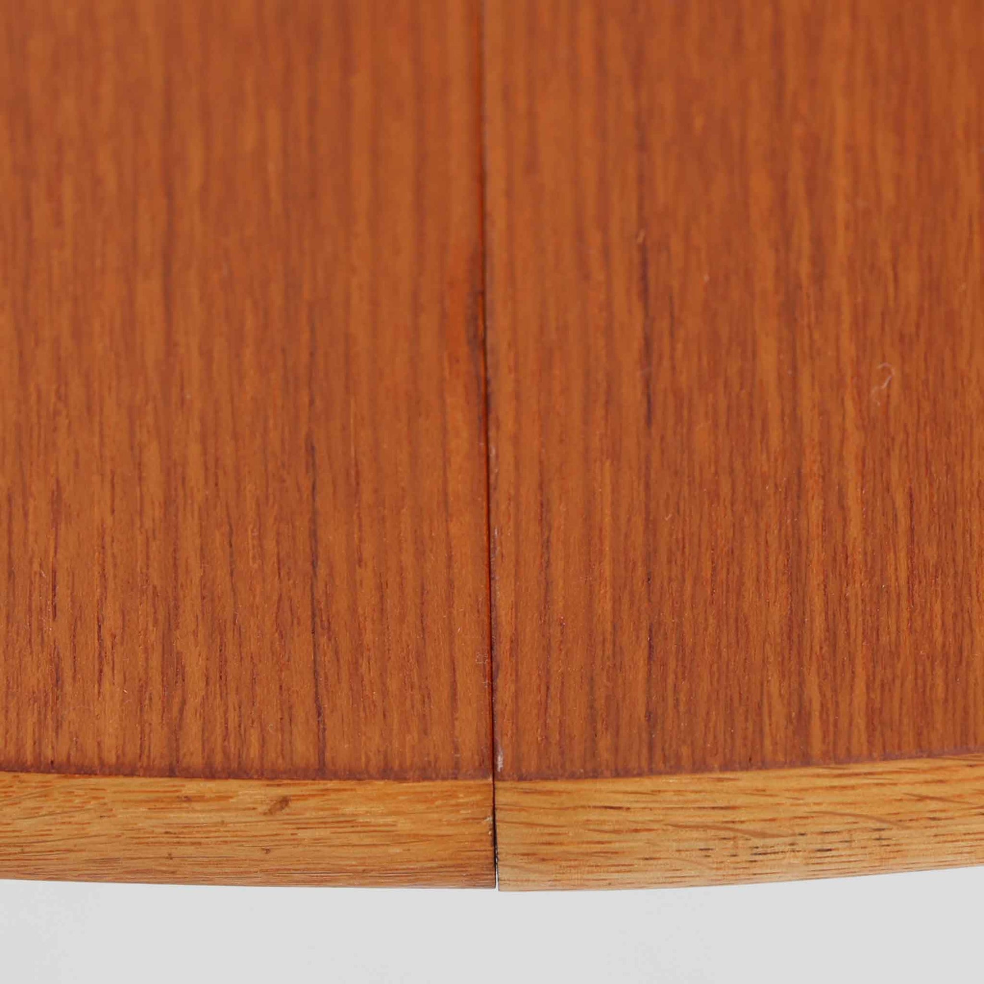 チーク材の天板とオーク材の脚部が美しく調和したこちらの円形エクステンションダイニングテーブルは、デンマーク製ならではの丁寧な仕上げと実用性が魅力の北欧ビンテージ家具です。直径110cmの円形天板は、中央に拡張板を2枚追加することで広々としたオーバル型に変化し、来客時やホームパーティーなどにも柔軟に対応できます。細身のテーパー脚が軽やかな印象を与え、温かみのある木の表情が空間に自然と溶け込む逸品です。