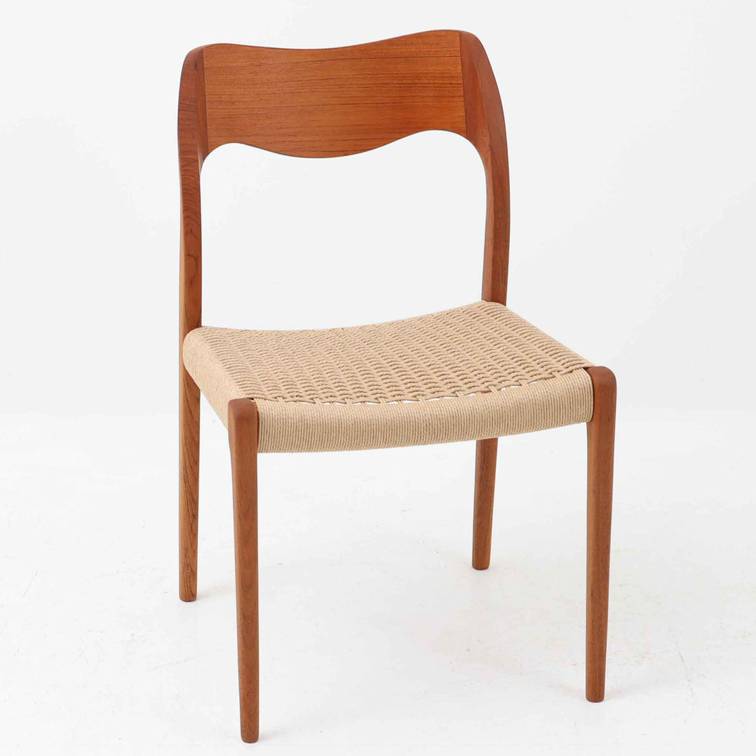 Niels Otto Mollerが手掛け、J.L. Mollers Mobelfabrik社によって製造されたModel 71は、チーク材とペーパーコードの美しい組み合わせが魅力の北欧ビンテージダイニングチェアです。背もたれから後脚へと流れるように繋がる柔らかな曲線が、身体を包み込むような快適な座り心地を生み出し、見た目にも優雅な印象を与えます。座面には職人の手作業によるペーパーコードが丁寧に張られ、自然素材ならではの温もりと耐久性を兼ね備えています。シンプルで洗練された佇まいは、ダイニングだけでなく書斎や玄関にも馴染みやすく、暮らしの中で長くご愛用いただける一脚です。ビンテージ品でのみ入手可能なチーク材のモデルです。