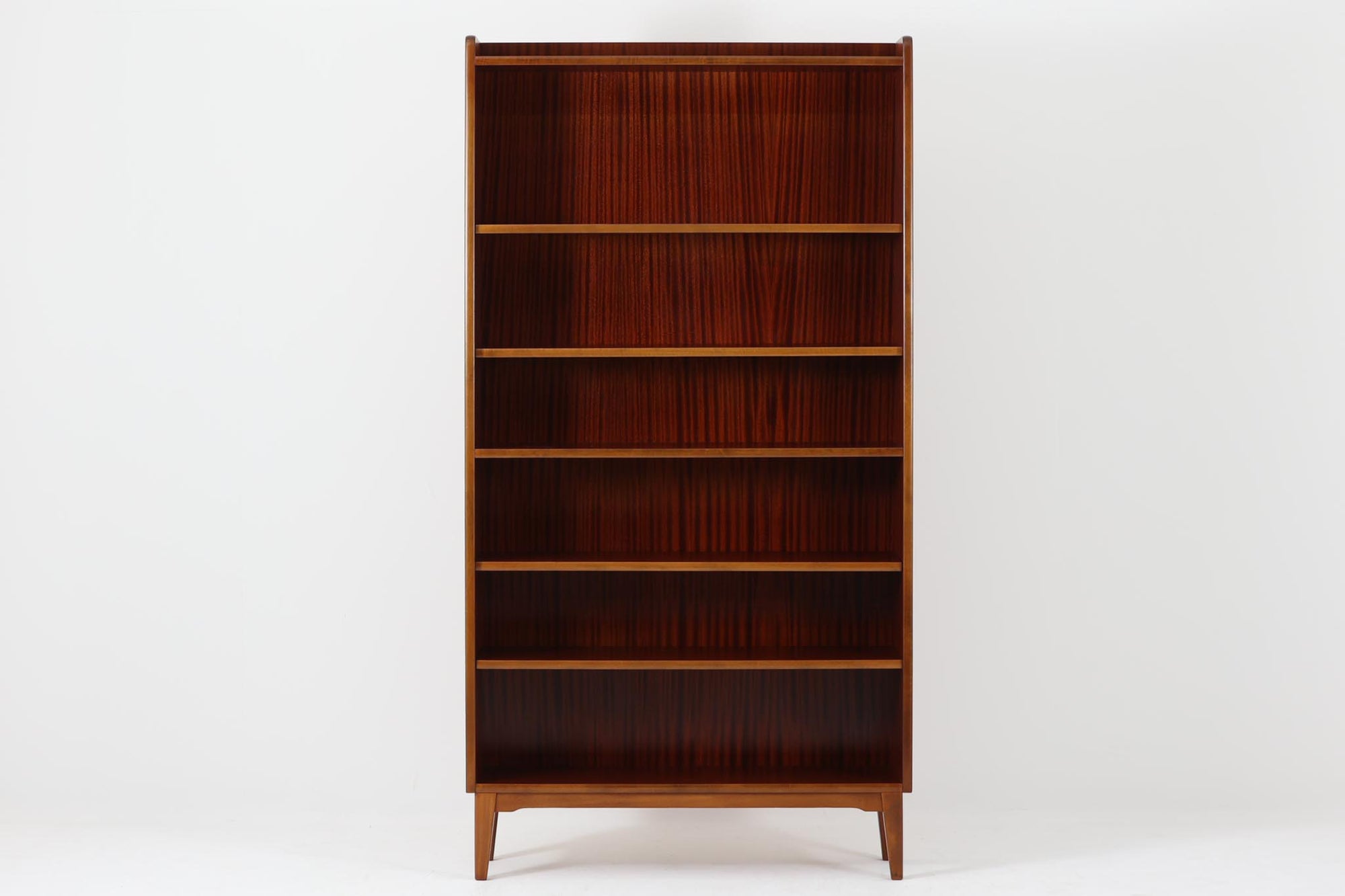 スウェーデンで製造されたヴィンテージのブックシェルフ。本体には深みのある美しいマホガニー材を使用し、縁や脚部にはナチュラルな風合いのビーチ材を組み合わせた、上品で洗練されたデザインが魅力です。特徴的なのは、上から下に向かって奥行が深くなる構造。視覚的な軽やかさを保ちながらも収納力を確保し、機能性とデザイン性を両立した作りになっています。脚部の緩やかな曲線が北欧家具らしいエレガントな印象を与え、インテリアに品のある温かみをプラスしてくれます。書籍やディスプレイアイテムを美しく収納できる、実用性とデザイン性を兼ね備えた一品。シンプルながらもこだわりを感じさせる北欧ヴィンテージ家具をお探しの方におすすめです。