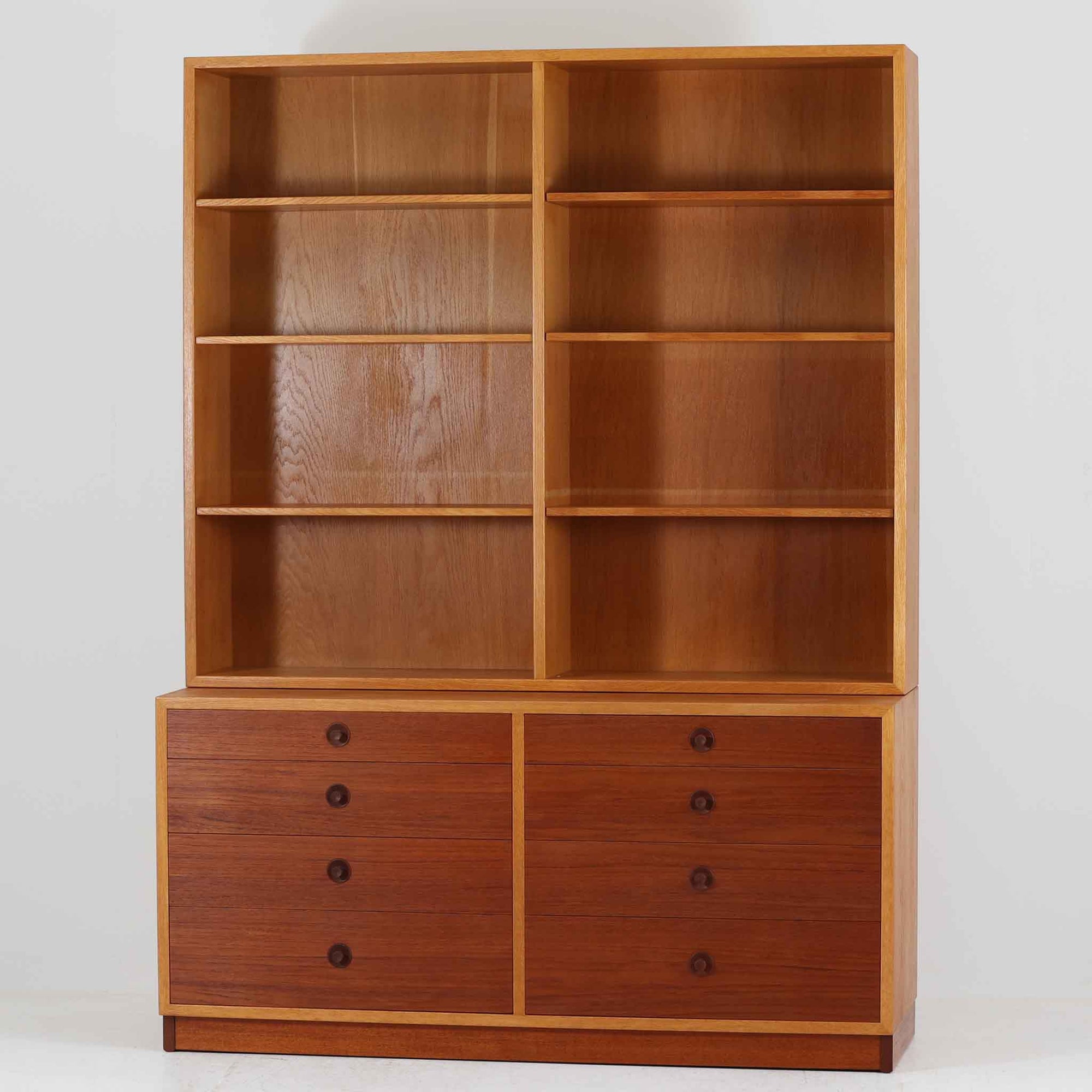 Borge Mogensenがデザインを手がけ、Karl Andersson社によって製造されたこちらのディスプレイシェルフは、チークとオークの異素材の美しいコントラストが際立つ北欧ビンテージ家具です。上段は可動式の棚板を備えたオープン収納、下段は左右に5杯ずつの引き出しを備え、収納力と機能性に優れた構成となっています。温かみのある木肌と丸型取手のアクセントが、空間に柔らかな印象を添えつつ、経年による風合いがヴィンテージらしい魅力を引き立てます。書斎やリビングでの書籍や雑貨の整理におすすめの一台です。