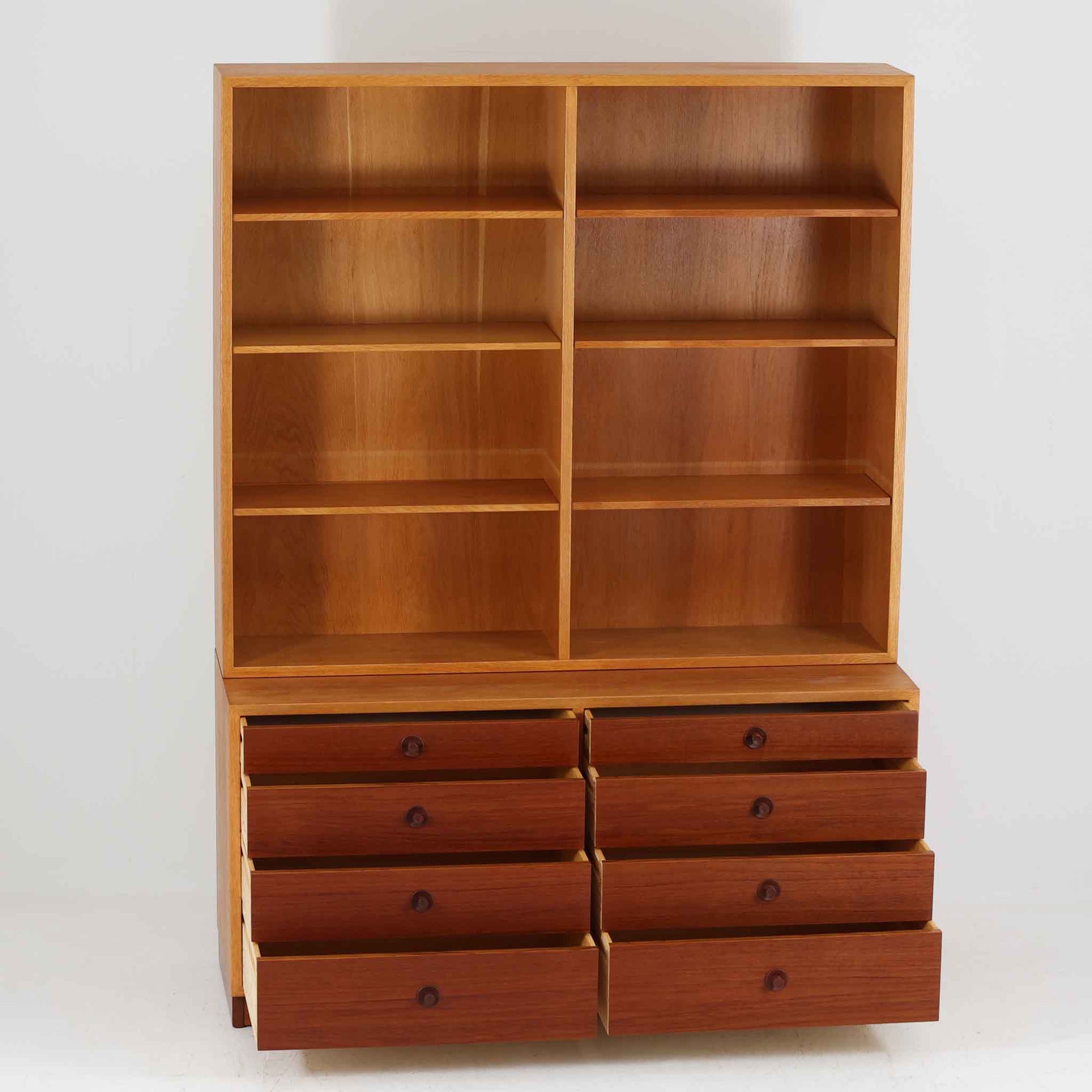 Borge Mogensenがデザインを手がけ、Karl Andersson社によって製造されたこちらのディスプレイシェルフは、チークとオークの異素材の美しいコントラストが際立つ北欧ビンテージ家具です。上段は可動式の棚板を備えたオープン収納、下段は左右に5杯ずつの引き出しを備え、収納力と機能性に優れた構成となっています。温かみのある木肌と丸型取手のアクセントが、空間に柔らかな印象を添えつつ、経年による風合いがヴィンテージらしい魅力を引き立てます。書斎やリビングでの書籍や雑貨の整理におすすめの一台です。