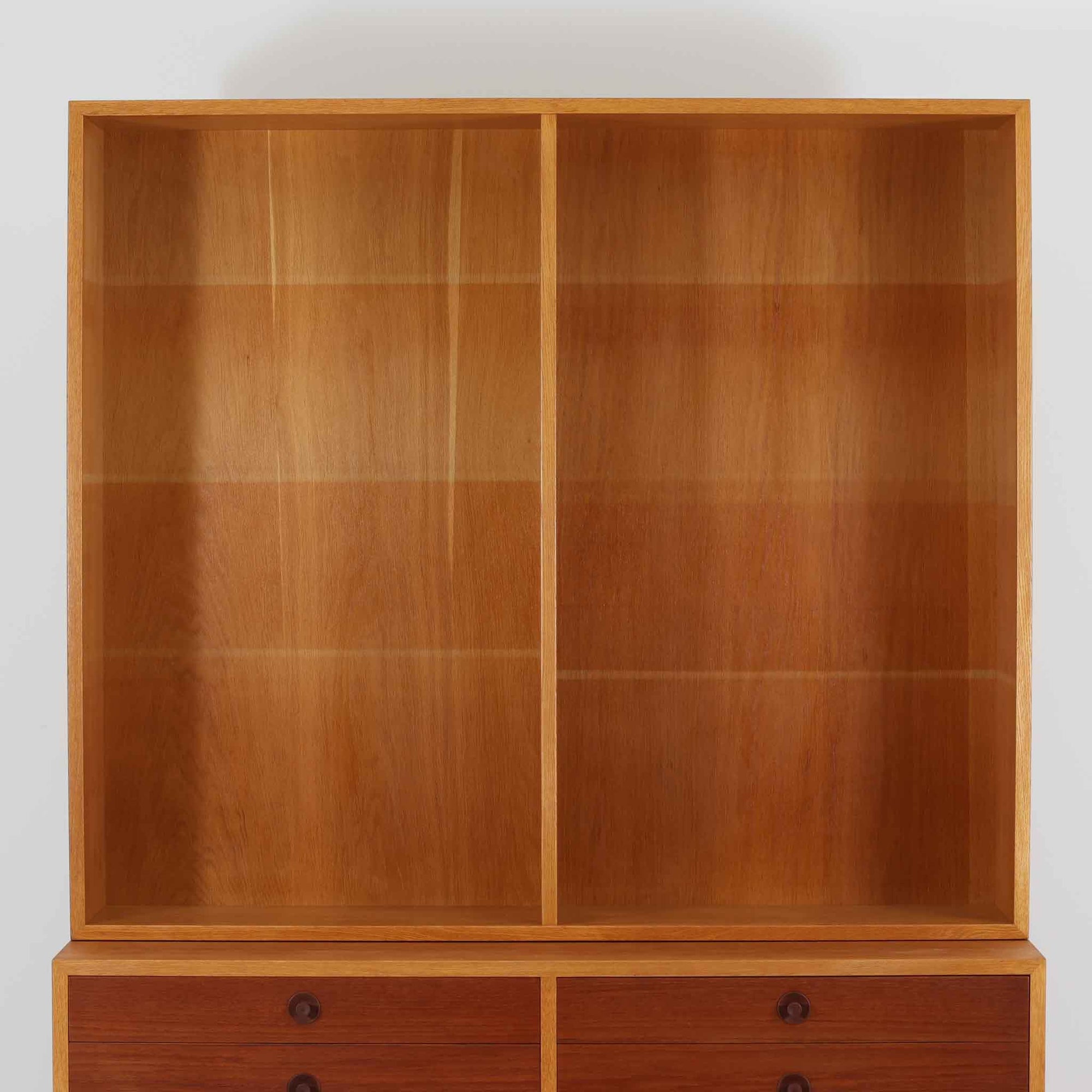 Borge Mogensenがデザインを手がけ、Karl Andersson社によって製造されたこちらのディスプレイシェルフは、チークとオークの異素材の美しいコントラストが際立つ北欧ビンテージ家具です。上段は可動式の棚板を備えたオープン収納、下段は左右に5杯ずつの引き出しを備え、収納力と機能性に優れた構成となっています。温かみのある木肌と丸型取手のアクセントが、空間に柔らかな印象を添えつつ、経年による風合いがヴィンテージらしい魅力を引き立てます。書斎やリビングでの書籍や雑貨の整理におすすめの一台です。