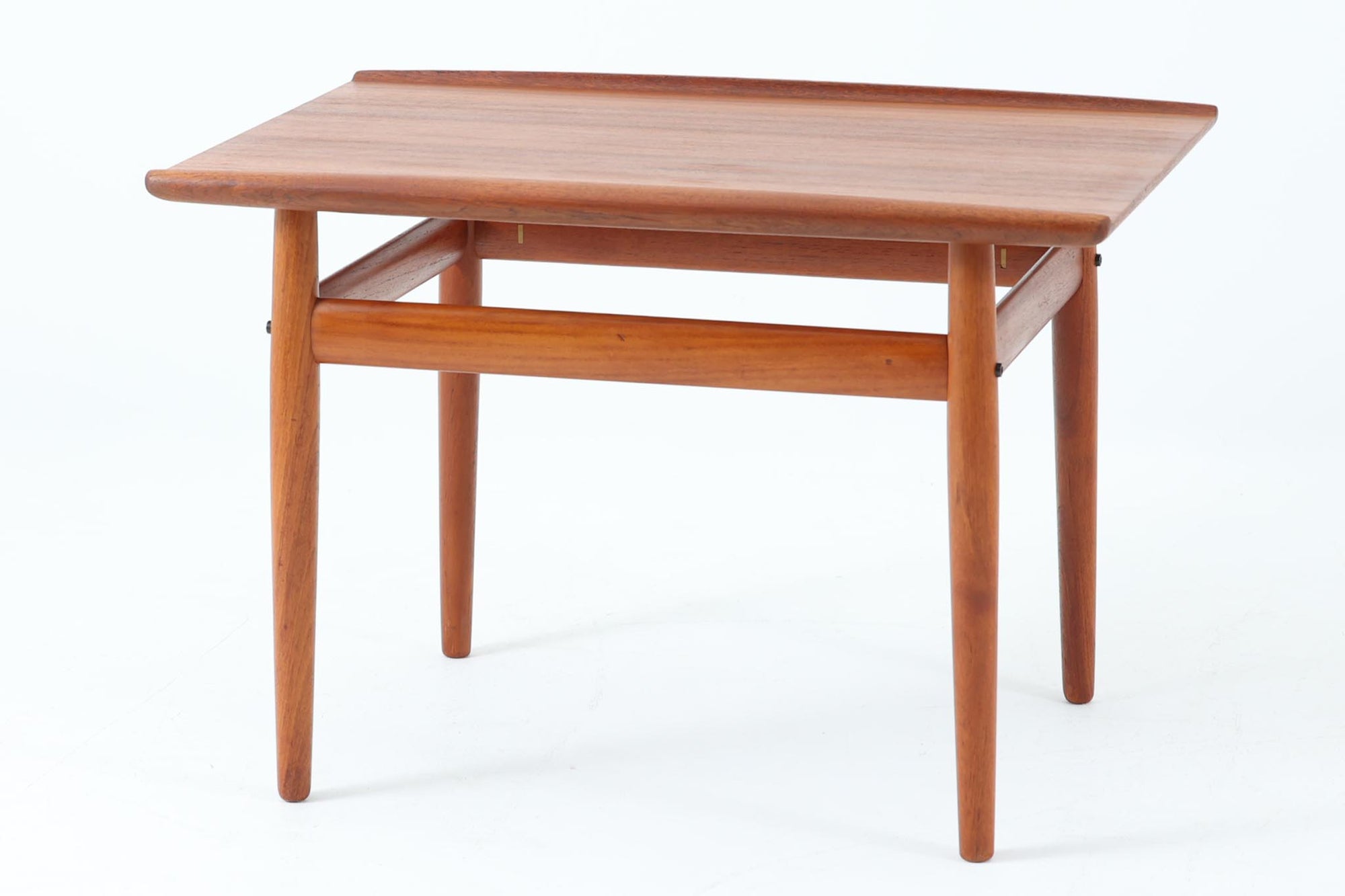 デンマークの女性デザイナー、グレーテ・ヤルクがデザインした1960年代のサイドテーブルです。Glostrup mobelfabrik社の製作による北欧モダンを代表する名作となっています。チーク材を贅沢に使用し、天板の緩やかな曲線と細身の脚部が美しいバランスを生み出しています。中段の横桟は、デザイン性と構造的な強度を両立。脚部は緩やかに外向きに設置され、安定感とエレガントさを兼ね備えています。コンパクトなサイズ感で、ソファサイドやベッドサイドなど様々な場所で活躍。現代のインテリアにも自然に溶け込む、時代を超えた普遍的なデザインの逸品です。