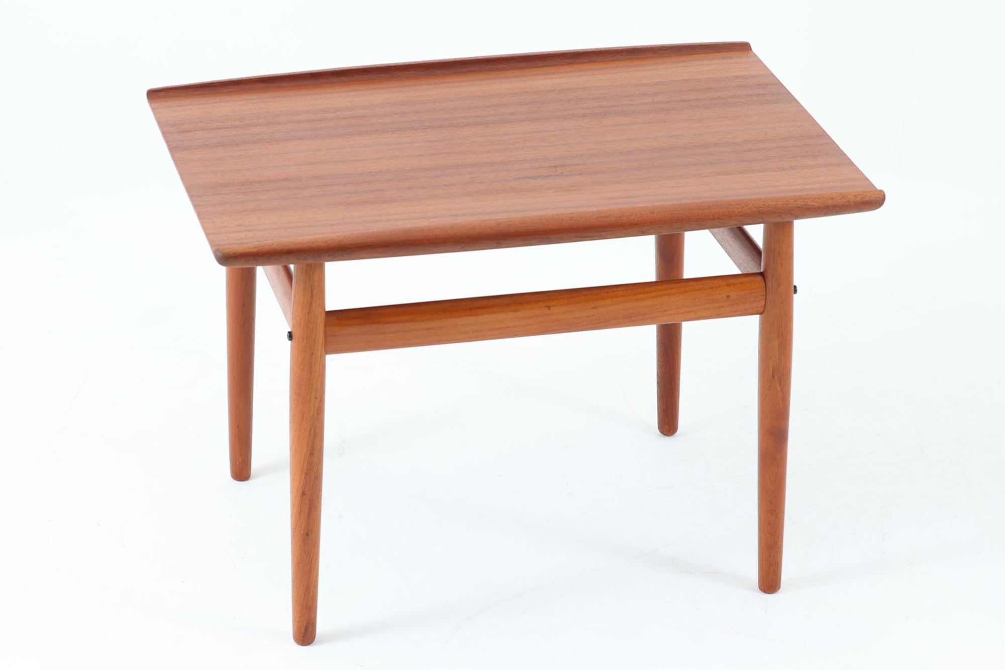 デンマークの女性デザイナー、グレーテ・ヤルクがデザインした1960年代のサイドテーブルです。Glostrup mobelfabrik社の製作による北欧モダンを代表する名作となっています。チーク材を贅沢に使用し、天板の緩やかな曲線と細身の脚部が美しいバランスを生み出しています。中段の横桟は、デザイン性と構造的な強度を両立。脚部は緩やかに外向きに設置され、安定感とエレガントさを兼ね備えています。コンパクトなサイズ感で、ソファサイドやベッドサイドなど様々な場所で活躍。現代のインテリアにも自然に溶け込む、時代を超えた普遍的なデザインの逸品です。