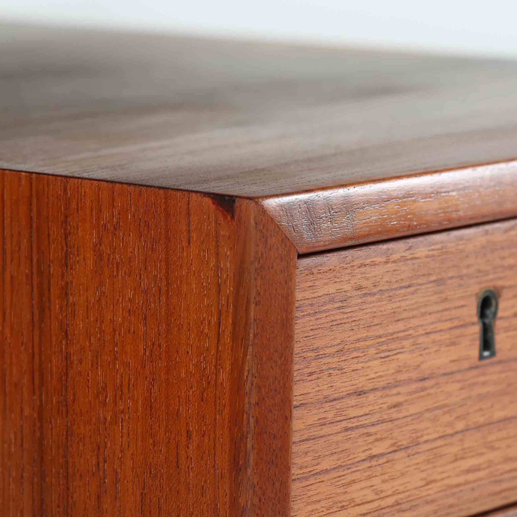 カイ・クリスチャンセンがデザインし、FM furniture社によって製造されたこちらの両袖デスクは、チーク材の美しい木目と温かみのある色合いが魅力の北欧ビンテージ家具です。左右には3杯ずつの引き出し、中央には扉付き収納を備え、背面にはオープンシェルフが設けられており、デスクとしての高い収納力と機能性を誇ります。壁付けはもちろん、間仕切りとしても活用できるため、空間の中心にも映える設計です。丸みを帯びた取手や脚部など、細部にまでこだわった意匠は、カイ・クリスチャンセンらしい洗練された美しさを体現しており、上質なワークスペースを演出します。