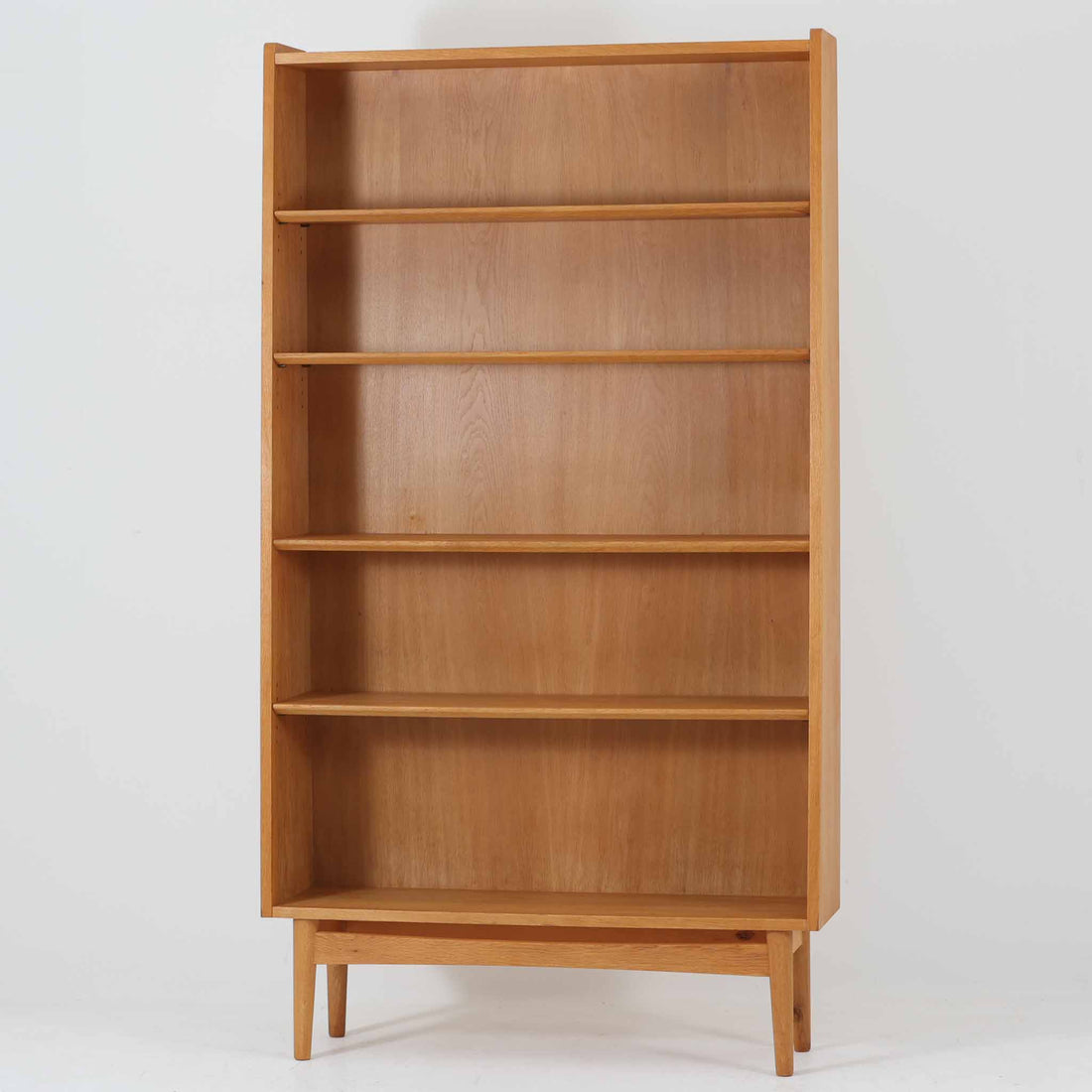 Johannes Sorthがデザインし、Bornholms Mobelfabrik社から1965年に製造されたこちらのブックシェルフは、美しい木目のオーク材と縦長のすっきりとしたフォルムが印象的な北欧ビンテージ家具で、豊富な棚板が本や雑貨の収納に優れた実用性を発揮します。裏面には「29 JUNI 1965」の刻印が残されており、当時のクラフトマンシップを感じさせる趣深い一台です。