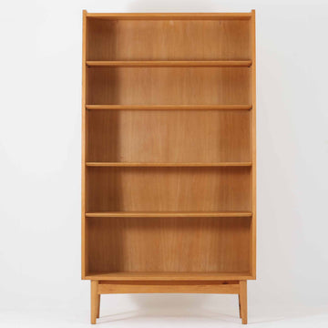 Johannes Sorthがデザインし、Bornholms Mobelfabrik社から1965年に製造されたこちらのブックシェルフは、美しい木目のオーク材と縦長のすっきりとしたフォルムが印象的な北欧ビンテージ家具で、豊富な棚板が本や雑貨の収納に優れた実用性を発揮します。裏面には「29 JUNI 1965」の刻印が残されており、当時のクラフトマンシップを感じさせる趣深い一台です。