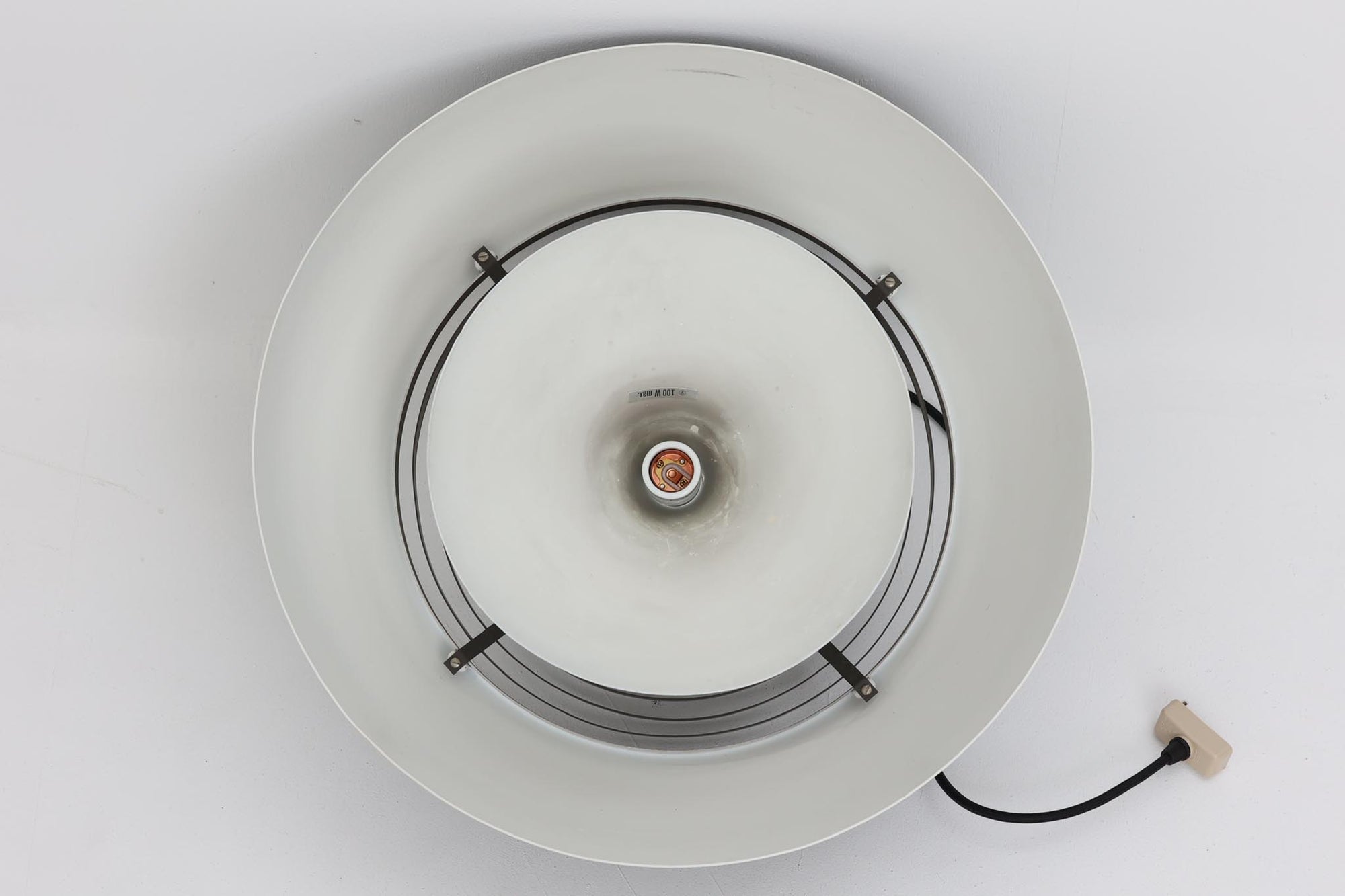 アルネ・ヤコブセンによってデザインされ、Louis Poulsen（ルイスポールセン）より製造されたAJロイヤル ペンダントライト。こちらは希少なグラファイトグレーカラーで、落ち着いたトーンが空間にシックな雰囲気を演出します。直径50cmの大型サイズで、光源を遮る構造と放射状に配置されたルーバーにより、眩しさを抑えた柔らかい光が空間全体を包み込みます。点灯時には上部のスリットから漏れる光も美しく、デザイン性と機能性を兼ね備えた一品です。外観には小傷や使用感がありますが、ビンテージならではの風合いとしてお楽しみいただけます。