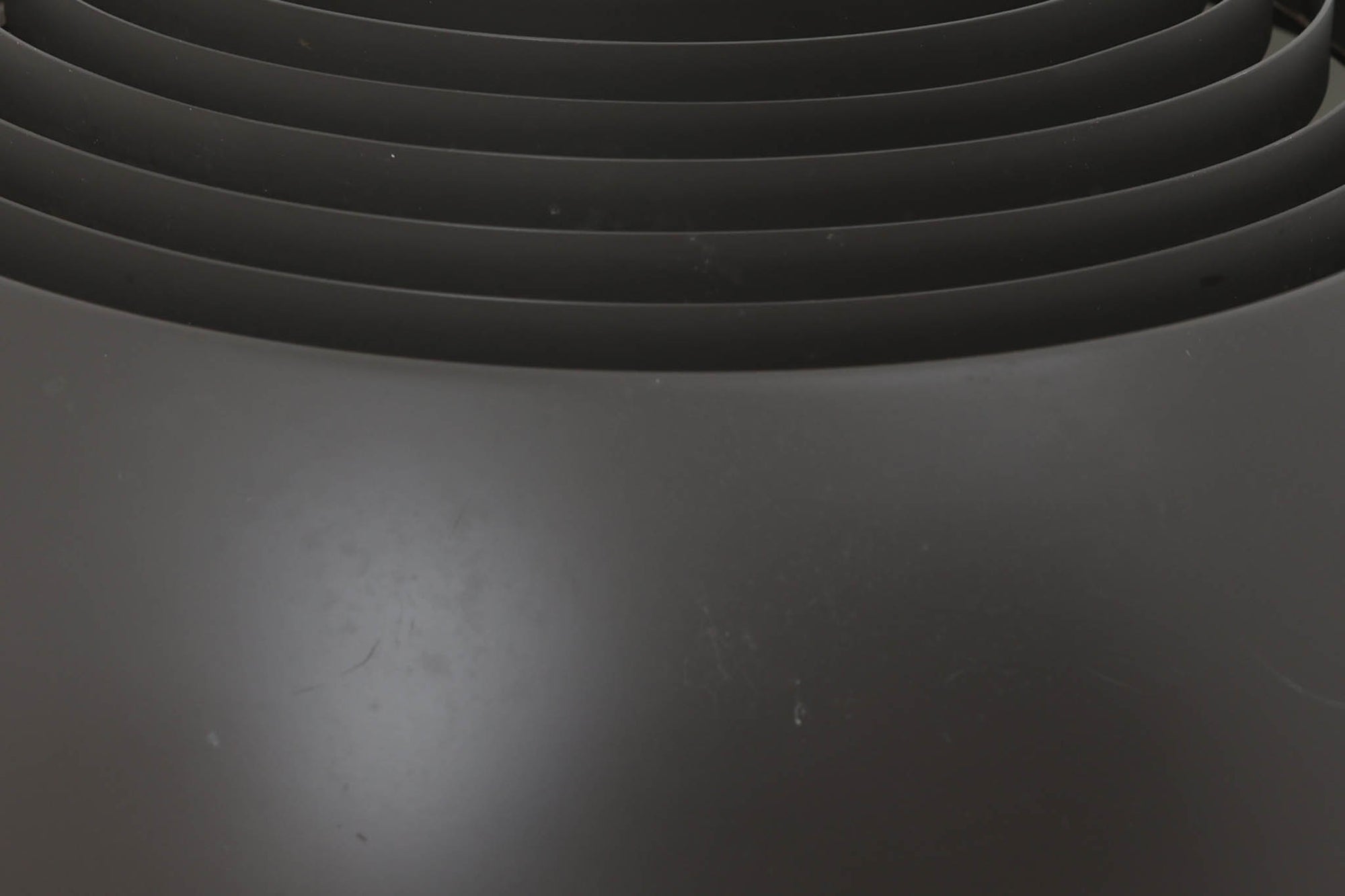 アルネ・ヤコブセンによってデザインされ、Louis Poulsen（ルイスポールセン）より製造されたAJロイヤル ペンダントライト。こちらは希少なグラファイトグレーカラーで、落ち着いたトーンが空間にシックな雰囲気を演出します。直径50cmの大型サイズで、光源を遮る構造と放射状に配置されたルーバーにより、眩しさを抑えた柔らかい光が空間全体を包み込みます。点灯時には上部のスリットから漏れる光も美しく、デザイン性と機能性を兼ね備えた一品です。外観には小傷や使用感がありますが、ビンテージならではの風合いとしてお楽しみいただけます。