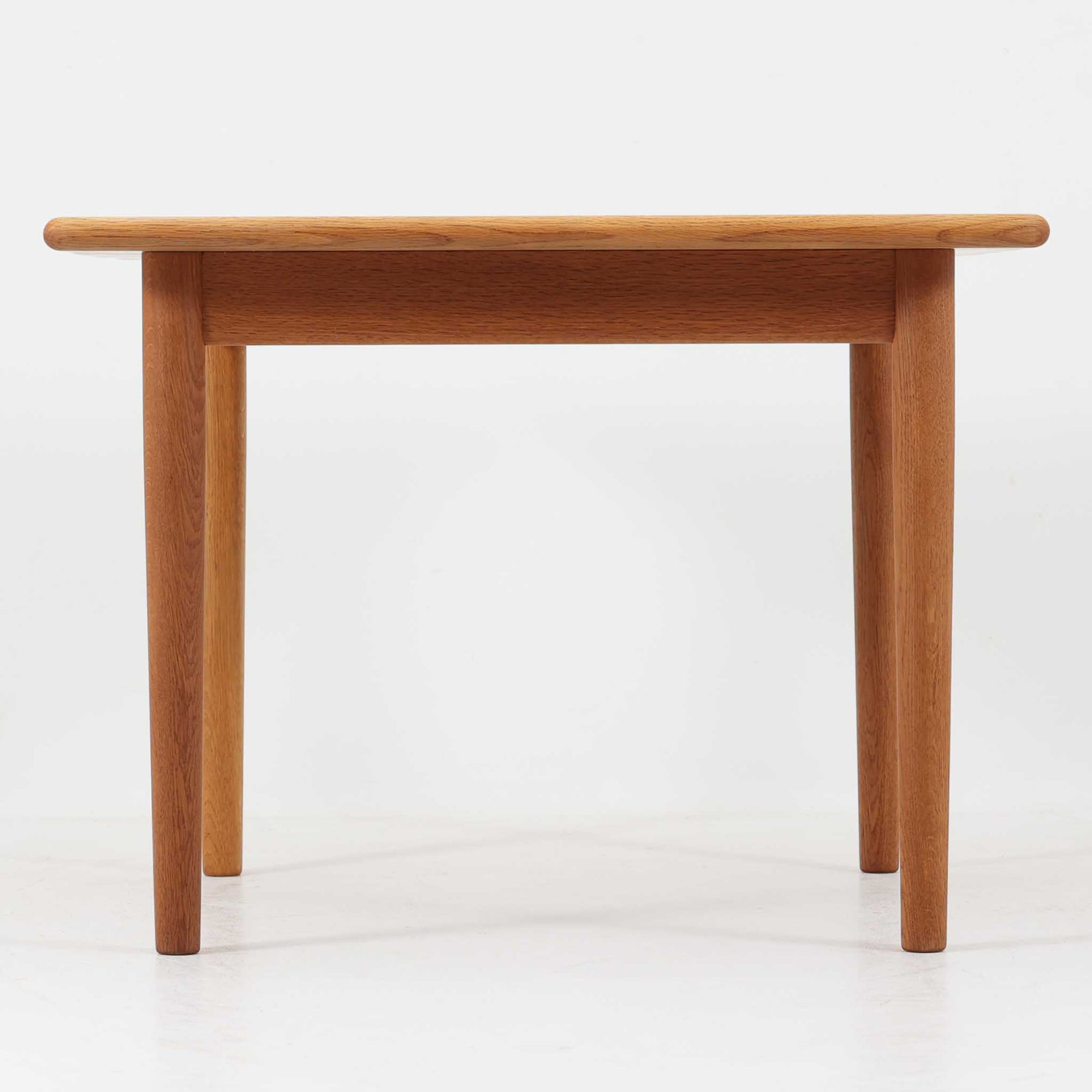 Hans J. WegnerがデザインしGetama社より製造されたGE80/86センターテーブルは、オーク無垢材を贅沢に使用した堅牢かつ端正な一台です。丸みを帯びた天板の縁や、すっきりとした円錐形の脚部が特徴で、シンプルでありながら温かみのある北欧デザインを体現しています。幅75cmと扱いやすいサイズ感で、リビングの中心に置いてコーヒーテーブルとしてはもちろん、サイドに添えても活躍する汎用性の高い家具です。経年による木肌の変化が深みを増し、ビンテージならではの存在感を放ちます。