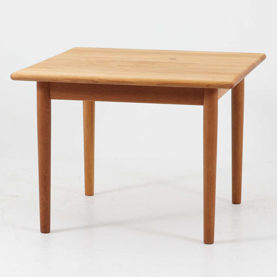 Hans J. WegnerがデザインしGetama社より製造されたGE80/86センターテーブルは、オーク無垢材を贅沢に使用した堅牢かつ端正な一台です。丸みを帯びた天板の縁や、すっきりとした円錐形の脚部が特徴で、シンプルでありながら温かみのある北欧デザインを体現しています。幅75cmと扱いやすいサイズ感で、リビングの中心に置いてコーヒーテーブルとしてはもちろん、サイドに添えても活躍する汎用性の高い家具です。経年による木肌の変化が深みを増し、ビンテージならではの存在感を放ちます。