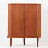 三角形のユニークなフォルムが目を引くこちらのコーナーキャビネットは、デンマーク製の北欧ビンテージ家具です。チーク材の温もりある木肌と、鍵付きのシンメトリーな扉が上品な佇まいを演出します。内部には棚板が2枚設けられており、日用品や雑貨などの収納に実用的。空間の角にすっきりと収まる設計は、デッドスペースを活かしながら、インテリアに程よいアクセントを加えてくれます。シンプルながら希少性を感じさせる一台です。