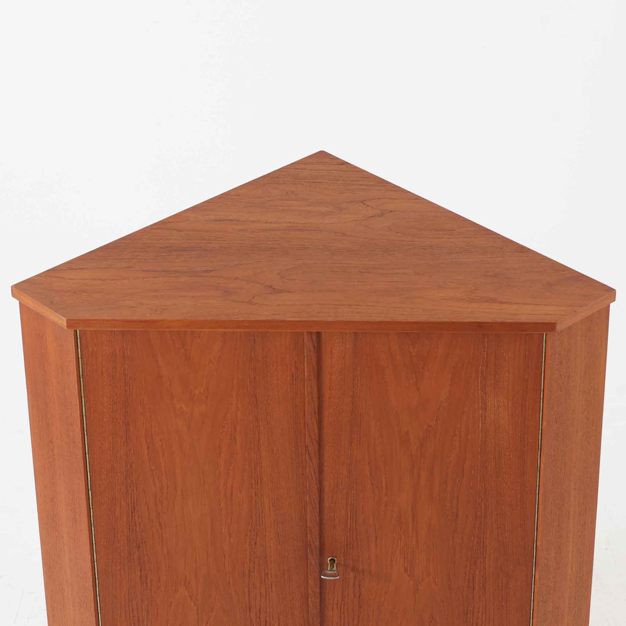 三角形のユニークなフォルムが目を引くこちらのコーナーキャビネットは、デンマーク製の北欧ビンテージ家具です。チーク材の温もりある木肌と、鍵付きのシンメトリーな扉が上品な佇まいを演出します。内部には棚板が2枚設けられており、日用品や雑貨などの収納に実用的。空間の角にすっきりと収まる設計は、デッドスペースを活かしながら、インテリアに程よいアクセントを加えてくれます。シンプルながら希少性を感じさせる一台です。